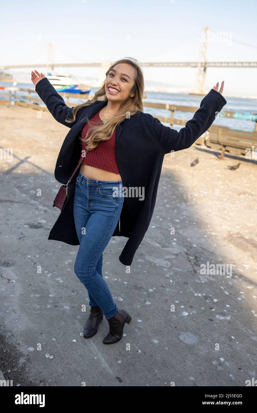 Jeune femme dansant avec joie sur l embarcadere avec le pont de la baie d Oakland en arriere plan Lifestyle local Tourism Photo Stock Alamy