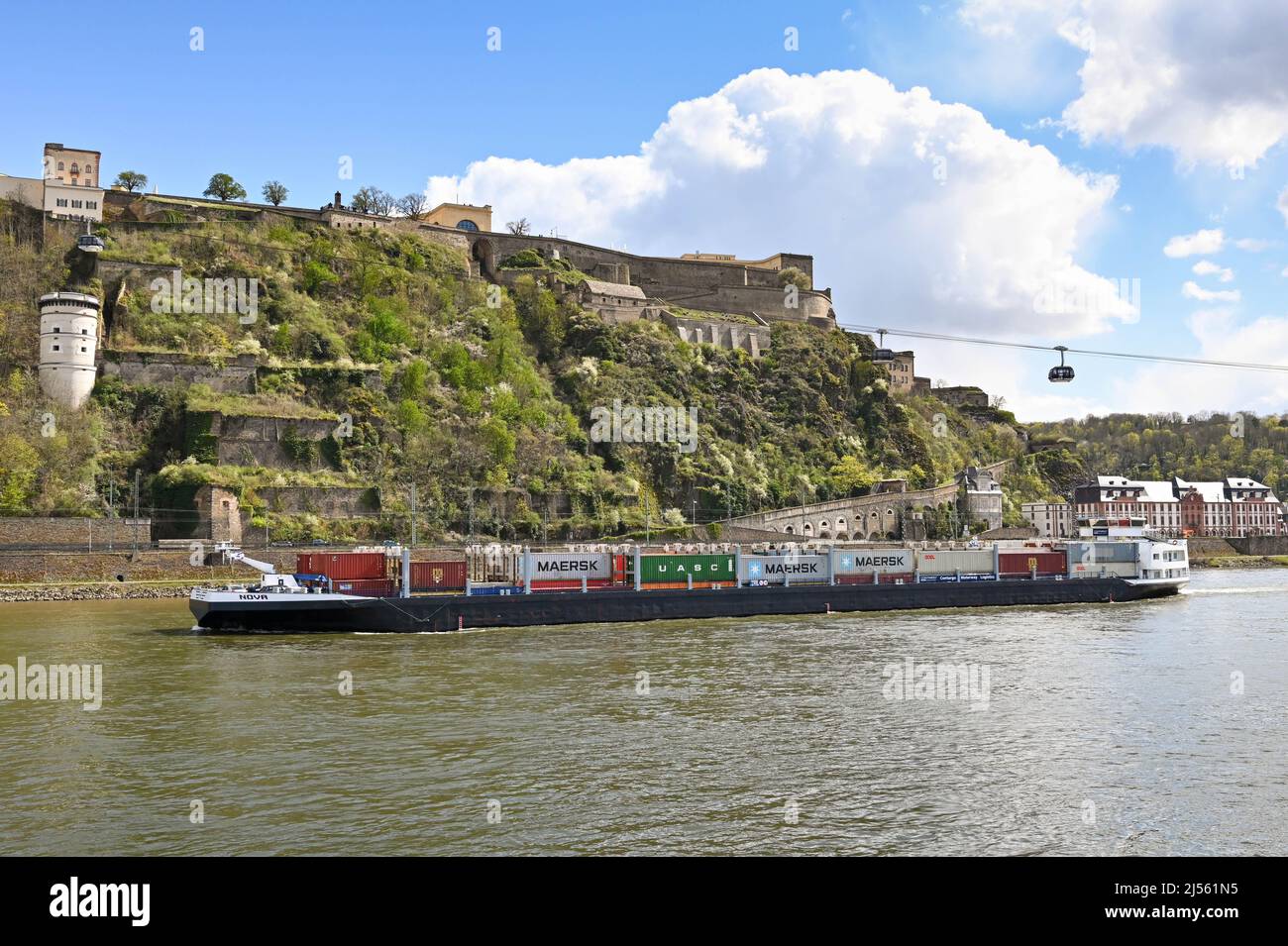 Koblenz, Allemagne – avril 2022 : barge industrielle transportant des conteneurs d'expédition sur le Rhin passant sous des téléphériques Banque D'Images