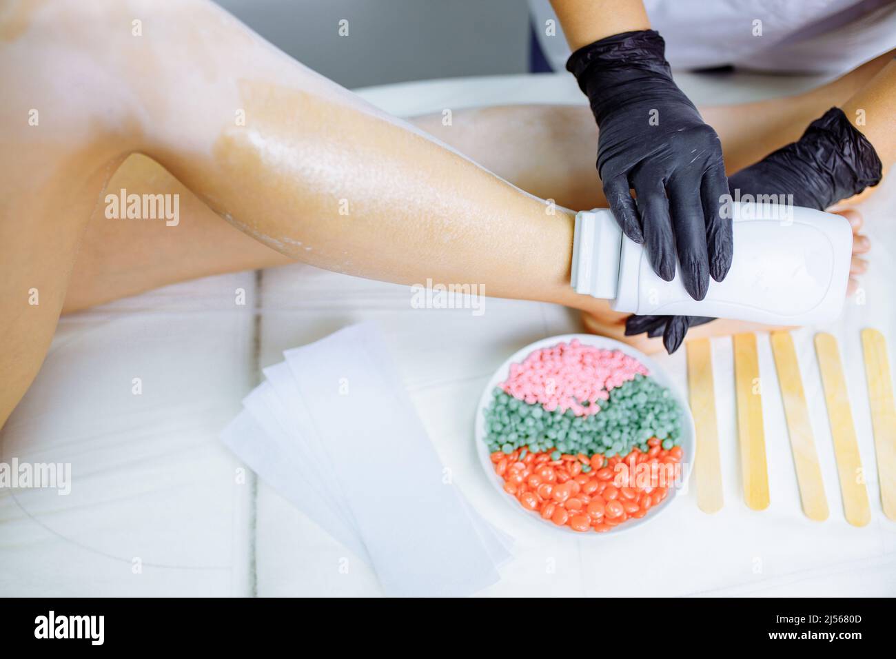 Sugaring: Femme au salon de cosmétiques cirant les jambes Banque D'Images