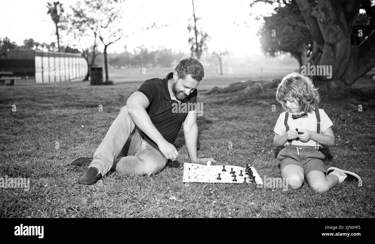 père et fils jouent aux échecs sur l'herbe dans le parc d'été, l'enfance Banque D'Images