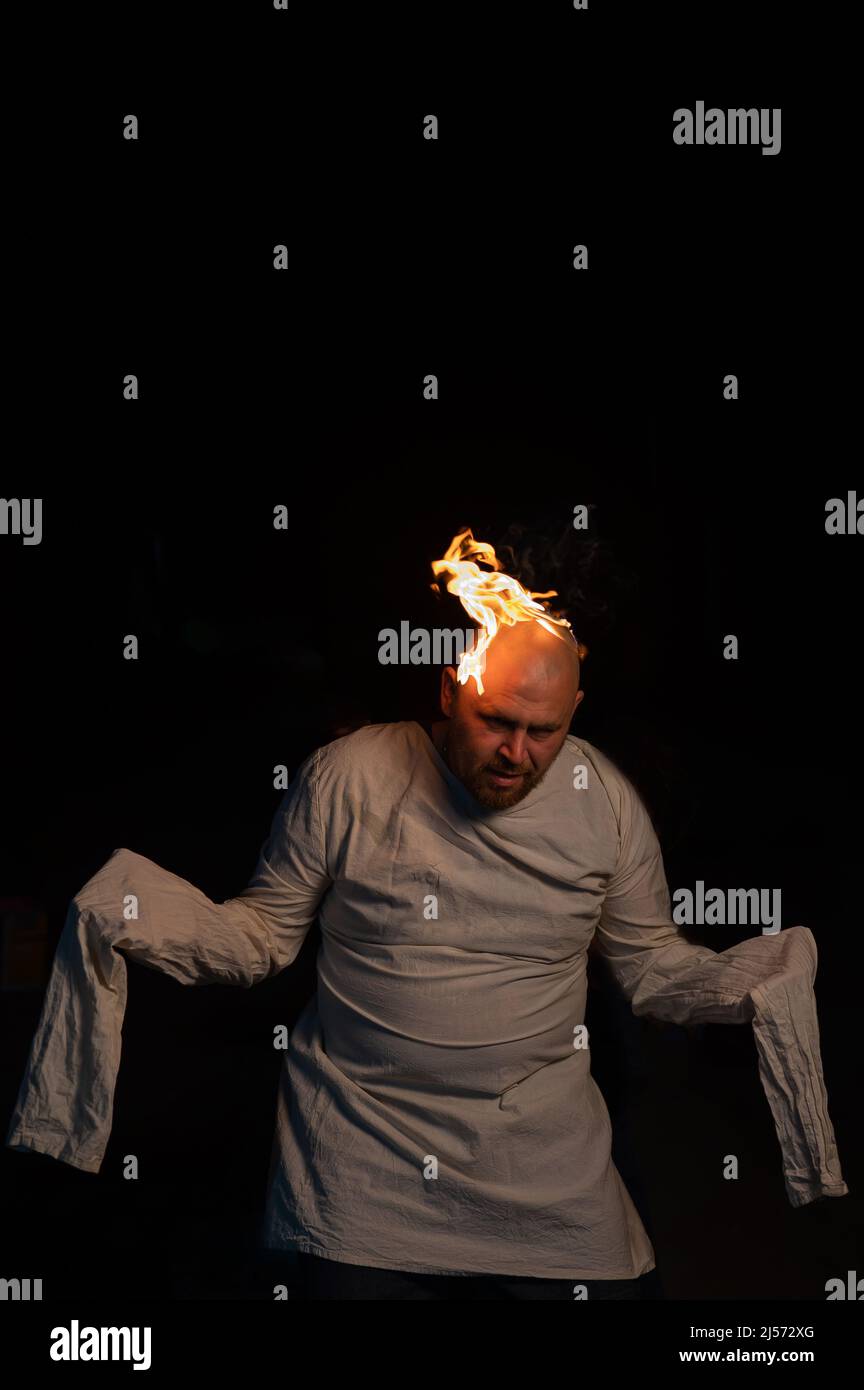 Homme chauve dans un blouson avec une tête brûlante sur un fond sombre. Banque D'Images