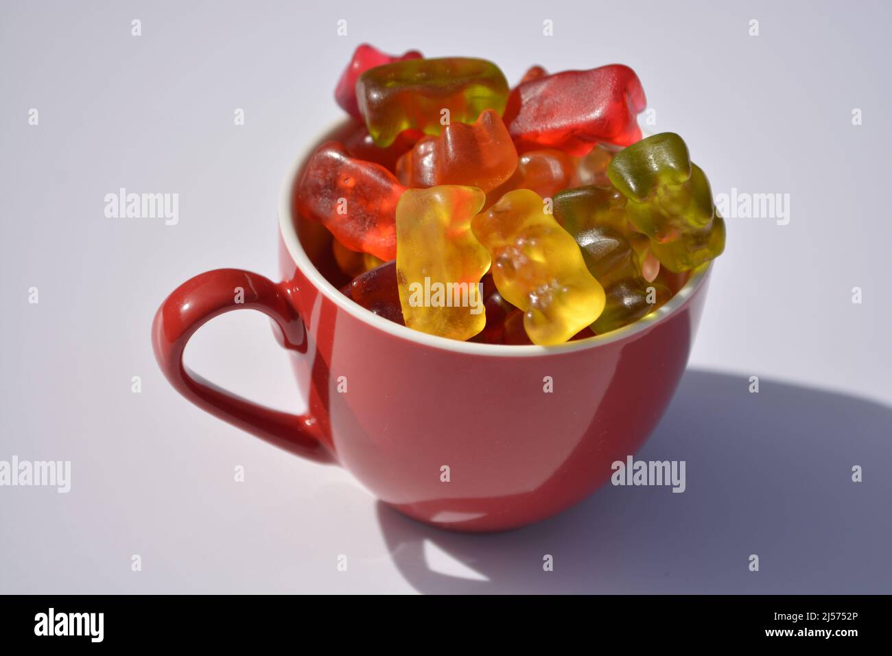 Bol avec friandises en gommeux mise au point sélective sur fond blanc au soleil Banque D'Images