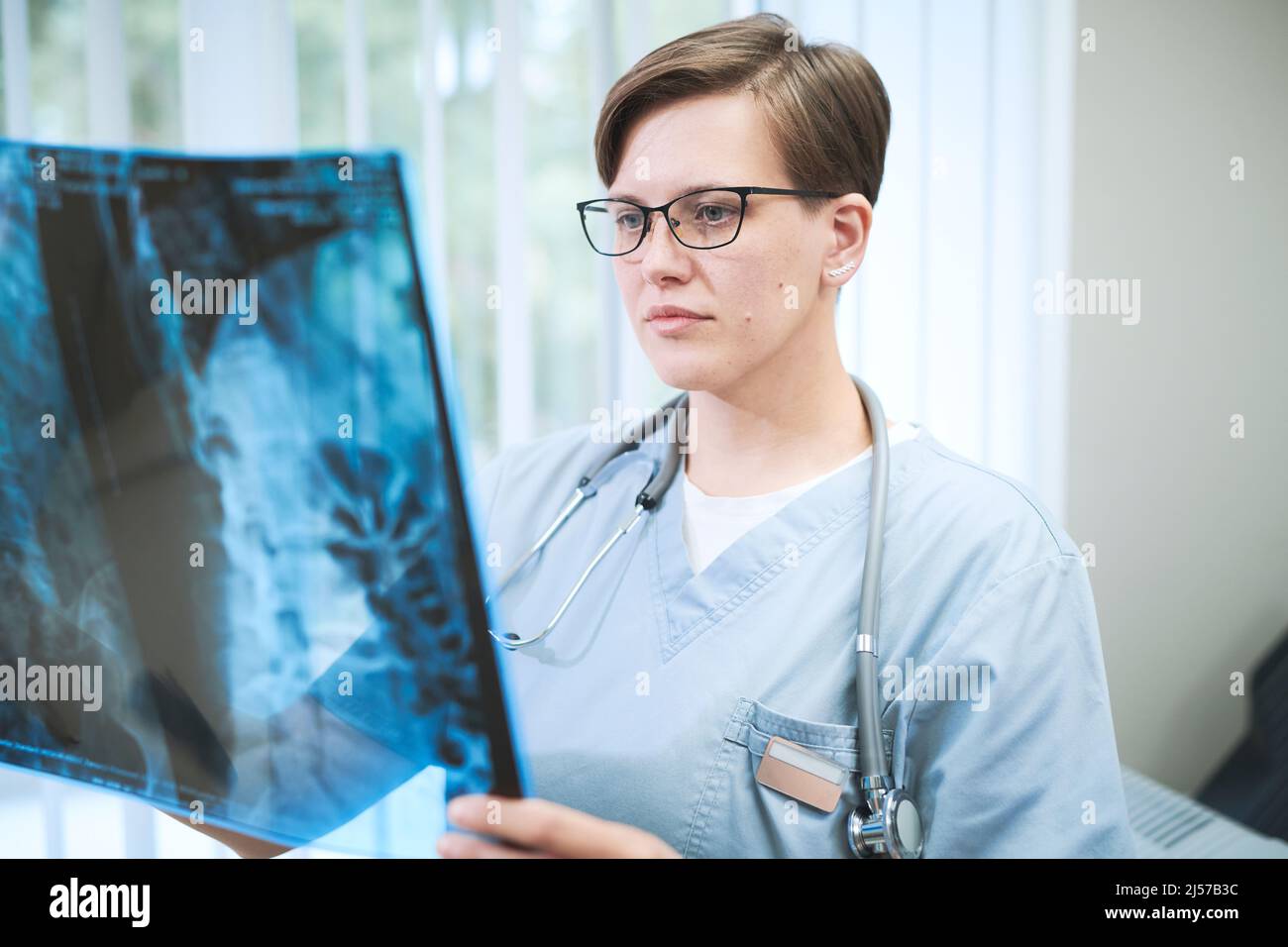 Jeune chirurgien caucasien sérieux avec stéthoscope autour du cou travaillant avec la tomodensitométrie du patient à l'hôpital Banque D'Images