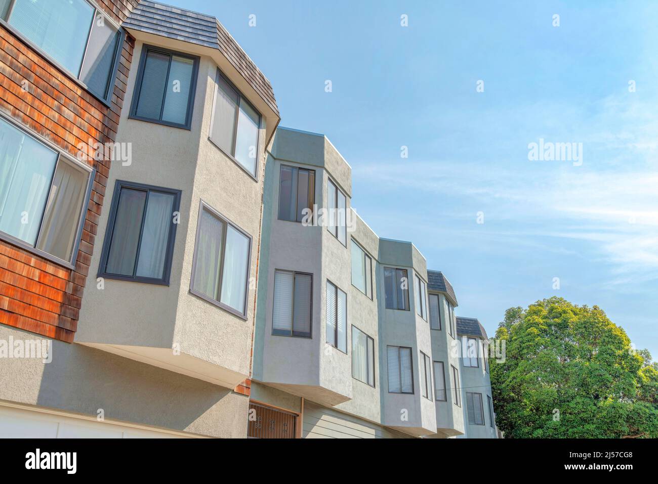 Vue à angle bas sur les maisons de ville avec baies vitrées et panneaux de bois à galets à San Francisco, Californie. Il y a une vue sur les fenêtres coulissantes en verre et les arbres Banque D'Images