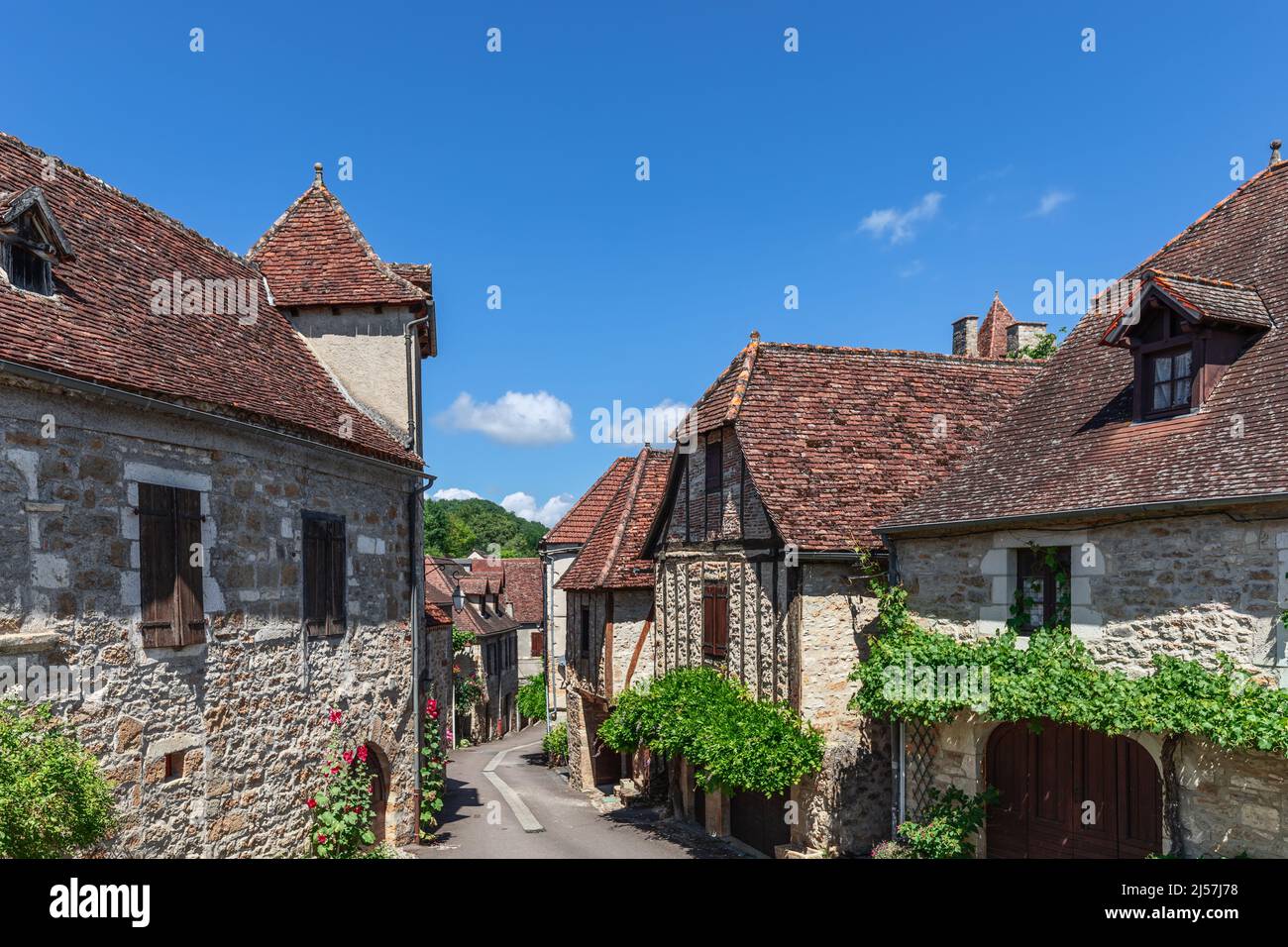 Ancienne rue étroite du village médiéval de Carennac, maisons en maçonnerie avec toits carrelés décorés de lierre et de plantes à fleurs. Lot, Quercy, France Banque D'Images
