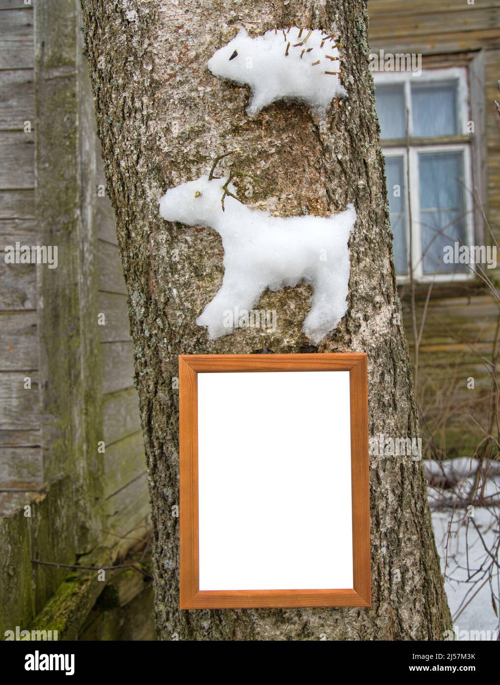 Les figures de neige (renne et hérisson) sont collées sur un tronc d'arbre. Projets créatifs d'hiver pour les enfants et les jeunes. Cadre pour félicitations Banque D'Images