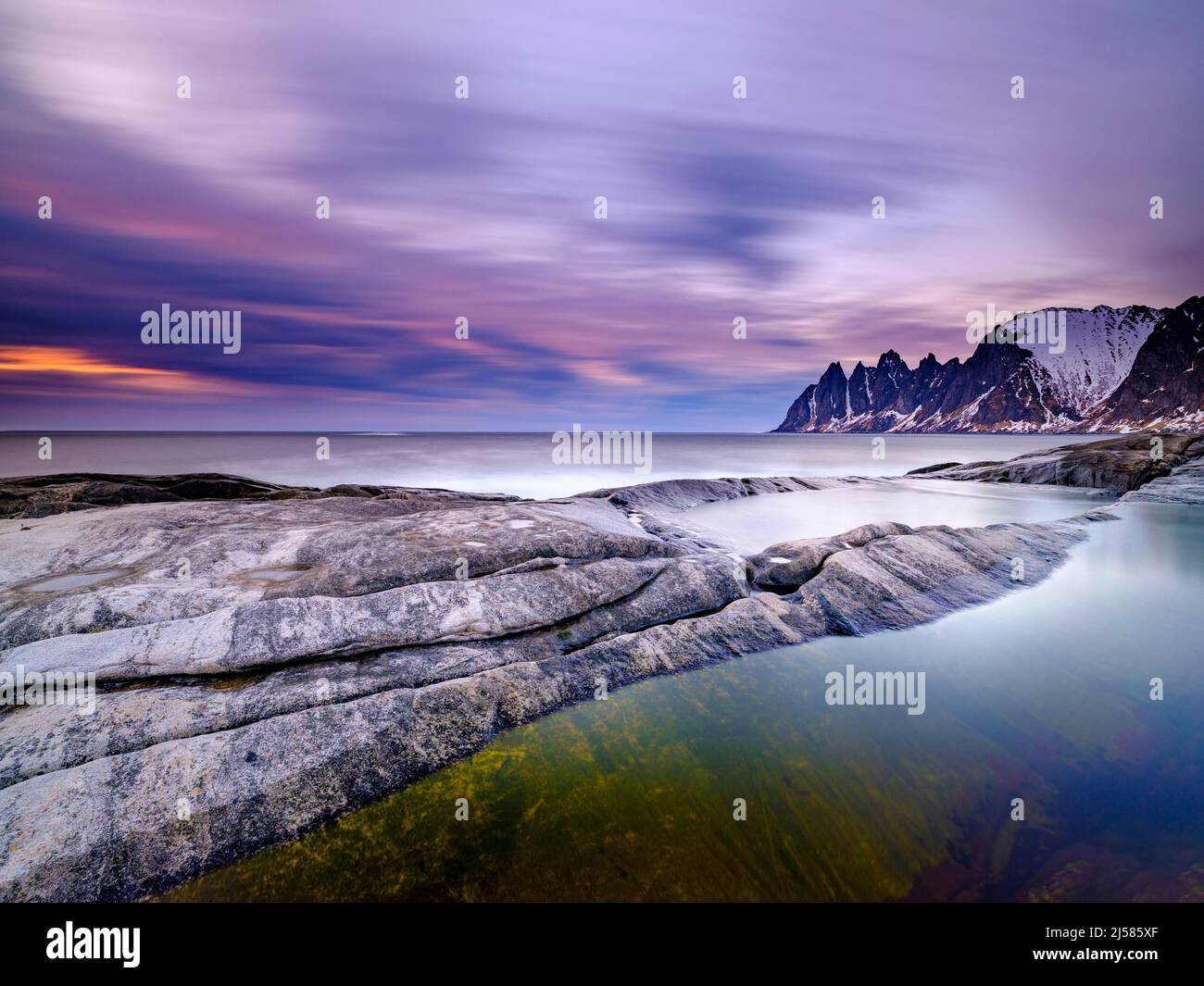 Piscine naturelle sur la plage de granit, le sommet des dents du Devils à l'arrière, la chaîne de montagnes d'Okshornan, Tungeneset, l'île de Senja, Troms, Norvège Banque D'Images