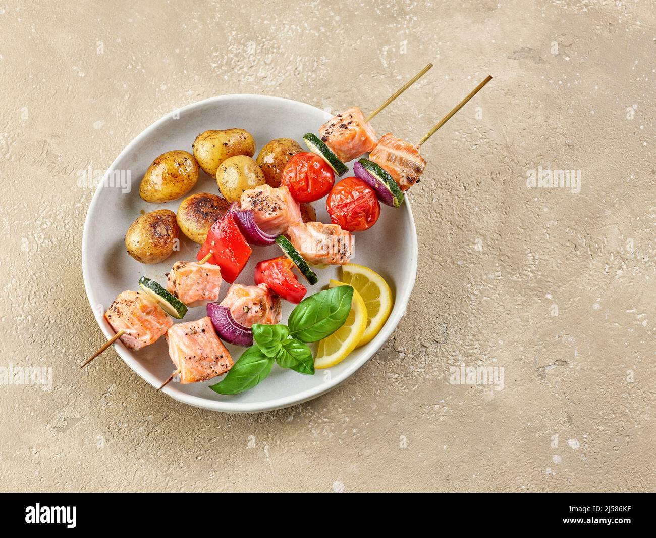 brochettes de saumon et de légumes avec pommes de terre rôties sur la table du restaurant, vue du dessus Banque D'Images brochettes de saumon et de légumes avec pommes de terre rôties sur la table du restaurant, vue du dessus Banque D'Images