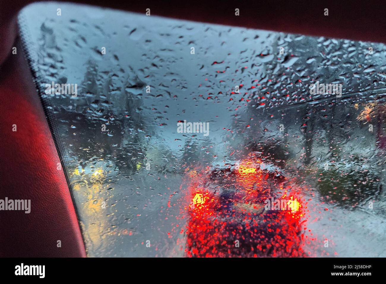 Blick aus dem Auto durch eine regengasse Scheibe mit unklarer Sicht auf den Verkehr am Abend, Witten, Ruhrgebiet, Deutschland Banque D'Images