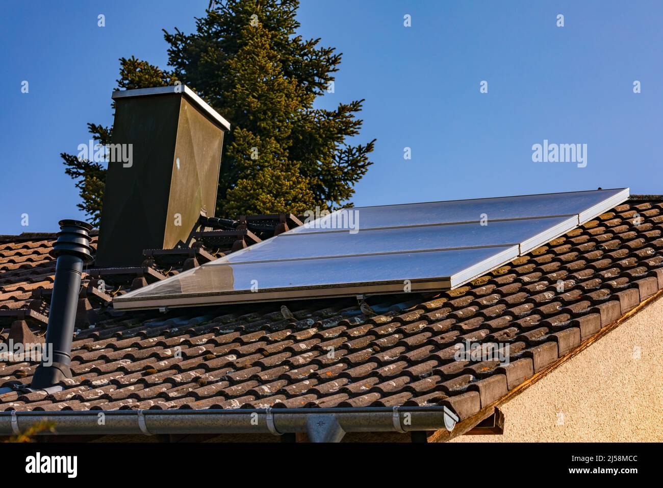 Les capteurs solaires sur le toit d'une maison transforment le rayonnement en eau chaude Banque D'Images