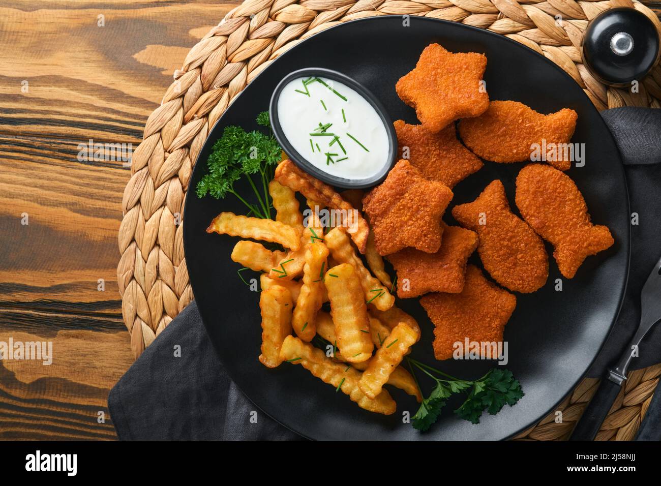 Fish and Chips, restauration rapide britannique. Bâtonnets de poisson avec frites sur plaque noire sur fond de table en bois. Plat traditionnel britannique authentique Banque D'Images