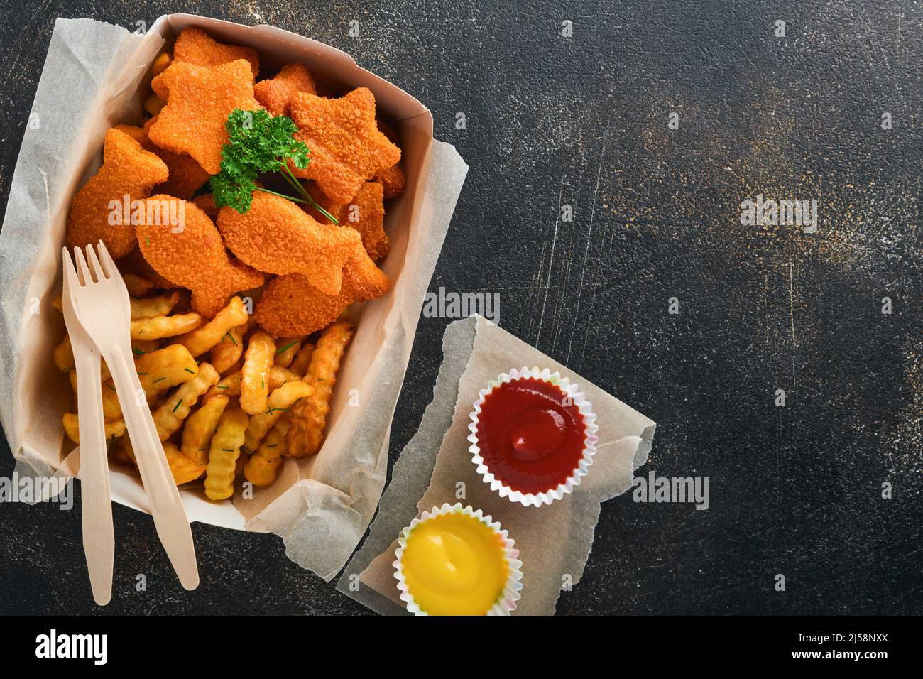Fish and Chips, restauration rapide britannique. Bâtonnets de poisson avec frites sur une plaque de papier à emporter sur fond de béton ancien sombre. Traditionnel anglais authe Banque D'Images