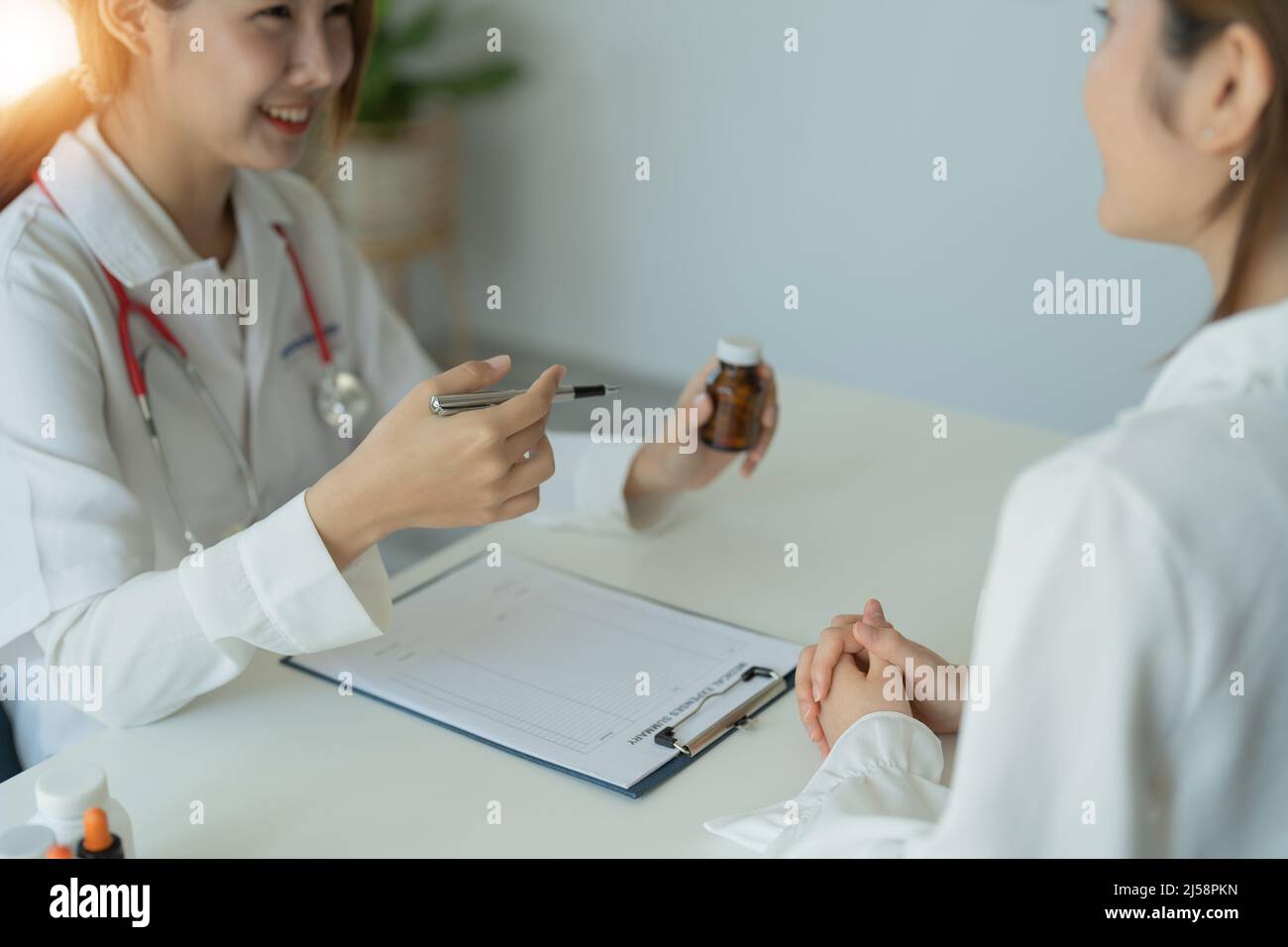 Une femme médecin donne un flacon de pilules au patient en clinique. Concept de soins de santé, de traitement médical et d'assurance Banque D'Images