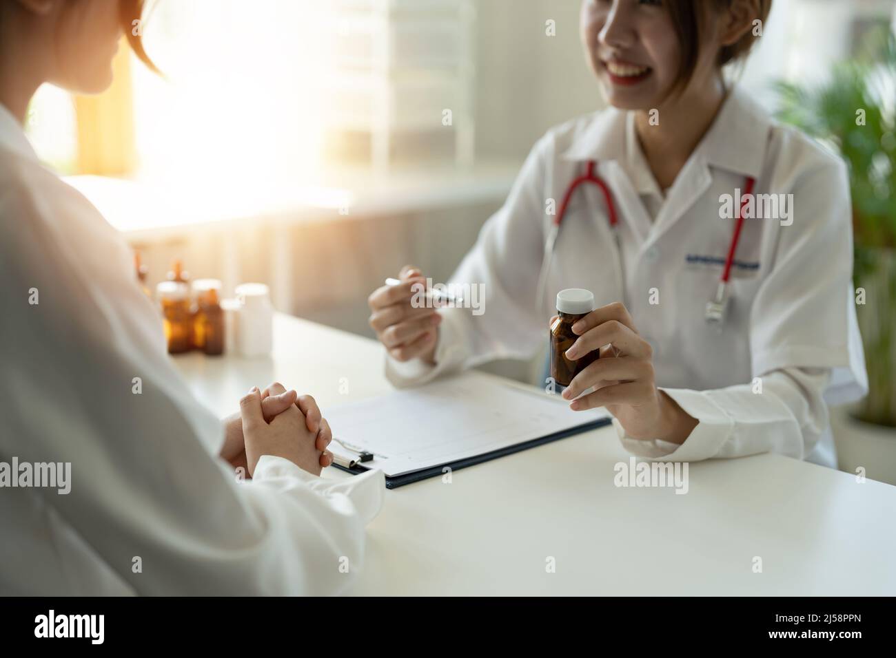 Une femme médecin donne un flacon de pilules au patient en clinique. Concept de soins de santé, de traitement médical et d'assurance Banque D'Images