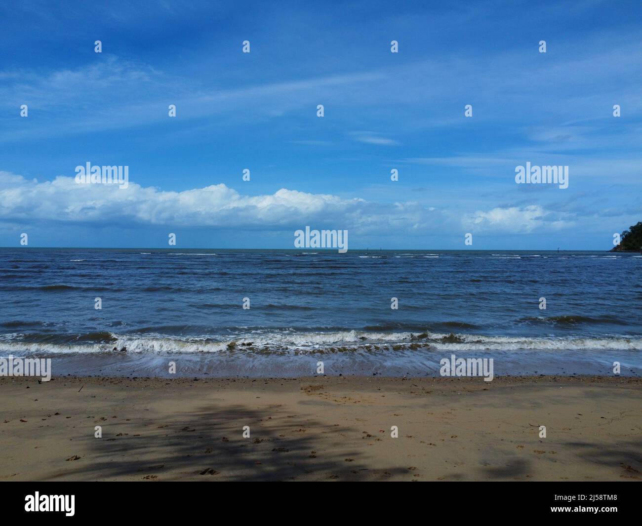 Vue sur les vagues s'écrasant sur la plage avec un ciel bleu Banque D'Images