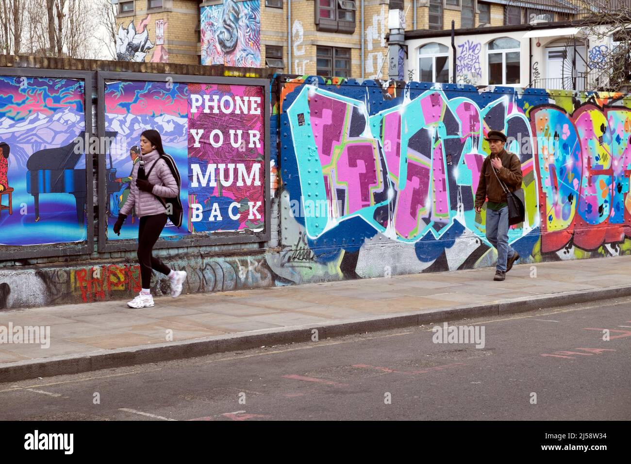Personnes personne marchant par graffiti coloré peinture sur des parures à Brick Lane Shoreditch printemps 2022 avril Londres Angleterre Royaume-Uni KATHY DEWITT Banque D'Images