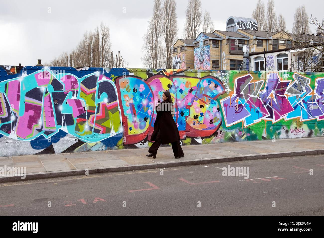 Personnes personne marchant par graffiti coloré peinture sur des parures à Brick Lane Shoreditch printemps 2022 avril Londres Angleterre Royaume-Uni KATHY DEWITT Banque D'Images