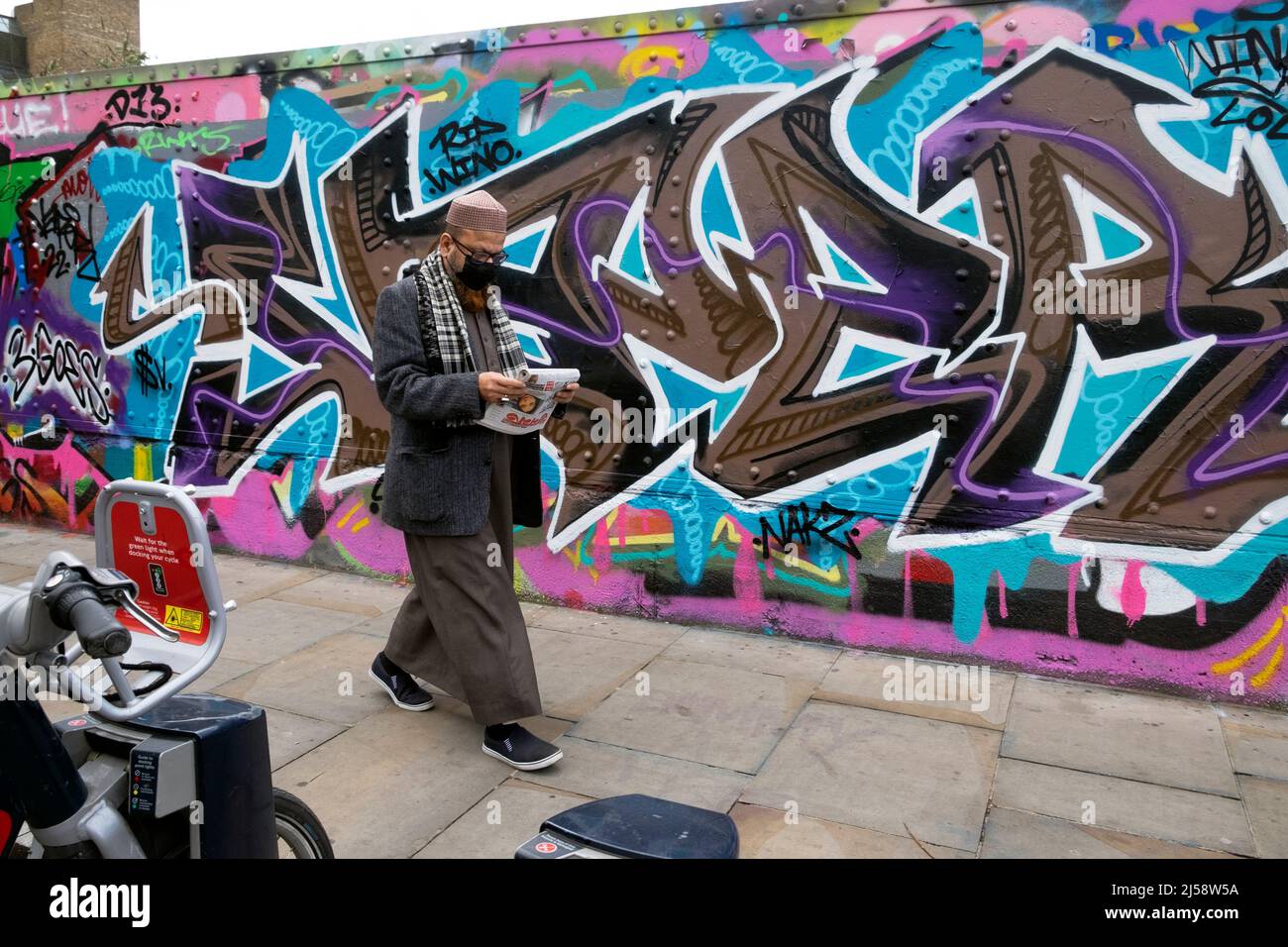 Personnes personne marchant par graffiti coloré peinture sur des parures à Brick Lane Shoreditch printemps 2022 avril Londres Angleterre Royaume-Uni KATHY DEWITT Banque D'Images