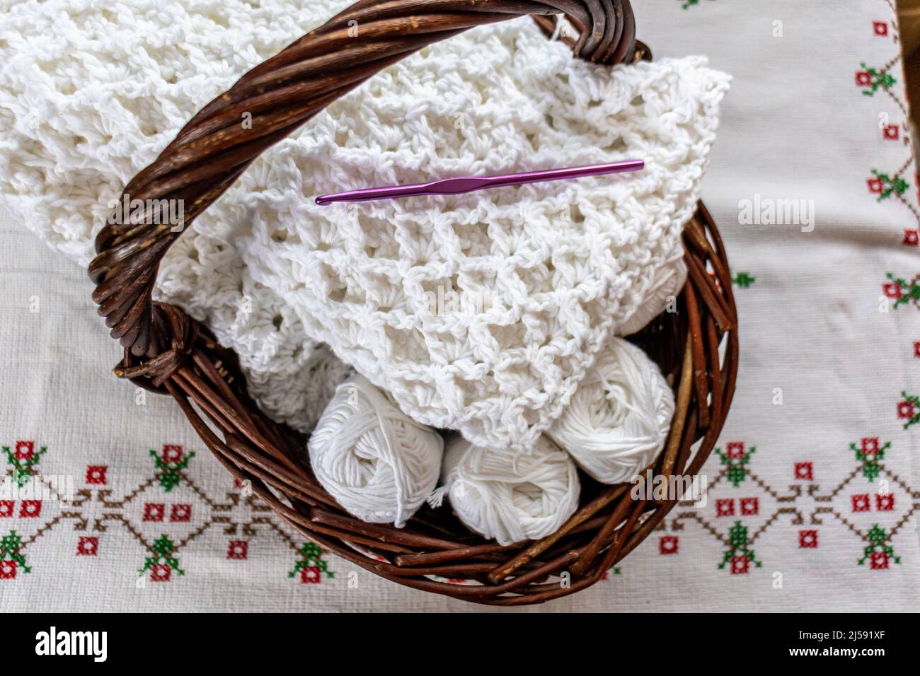 Boules de coton, une couverture partiellement finie avec un motif original  en crochet gaufré, crochet en crochet violet dans un panier en osier brun,  nappe Photo Stock - Alamy