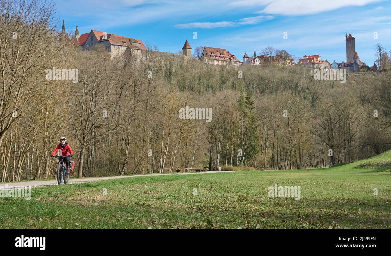 Belle femme de la ville lors d'une visite à vélo sur la célèbre route allemande des châteaux, au-dessous de la ligne d'horizon médiévale de Rothenburg ob der Tauber, Bavière, Allemagne Banque D'Images