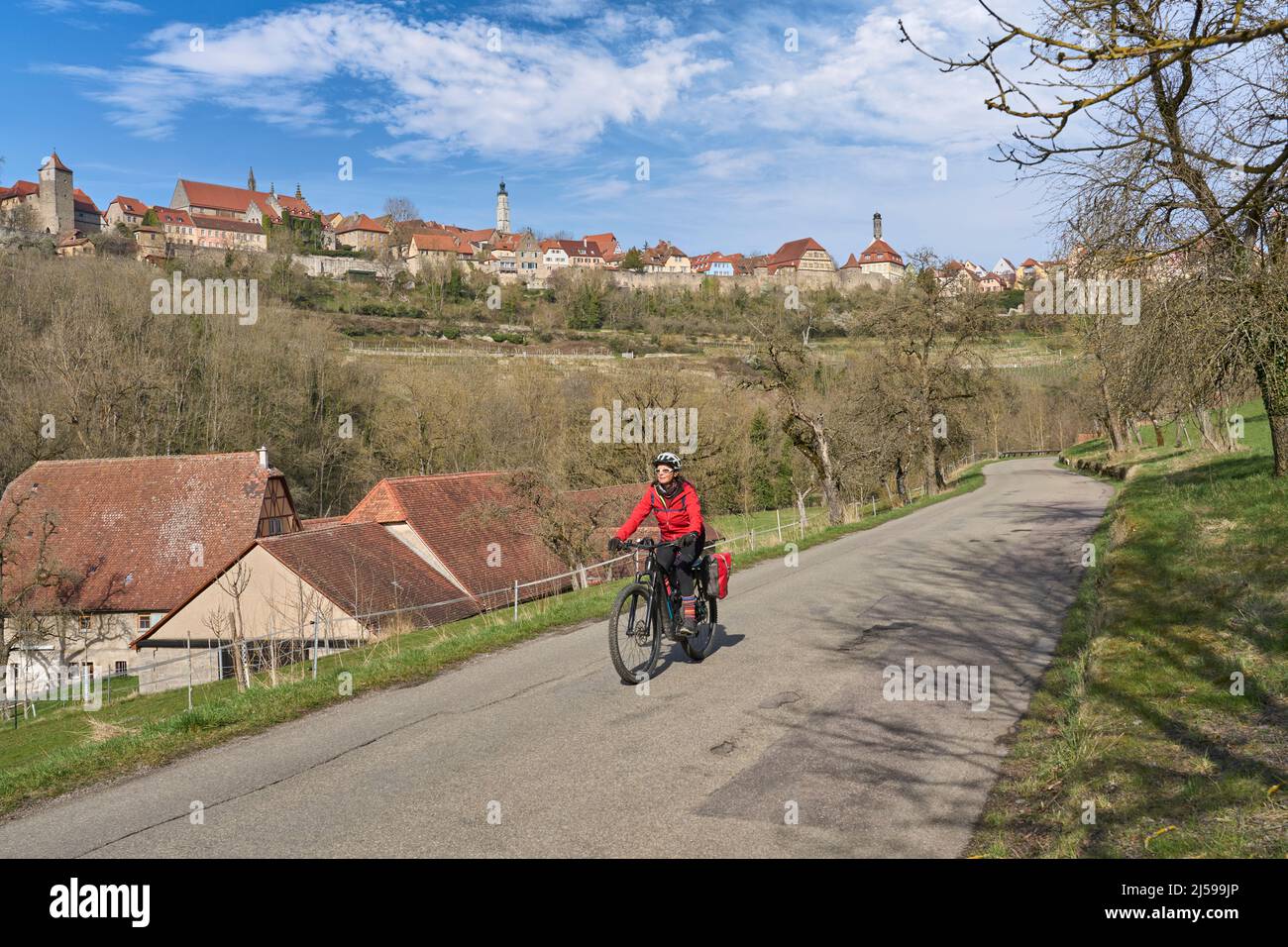 Belle femme de la ville lors d'une visite à vélo sur la célèbre route allemande des châteaux, au-dessous de la ligne d'horizon médiévale de Rothenburg ob der Tauber, Bavière, Allemagne Banque D'Images