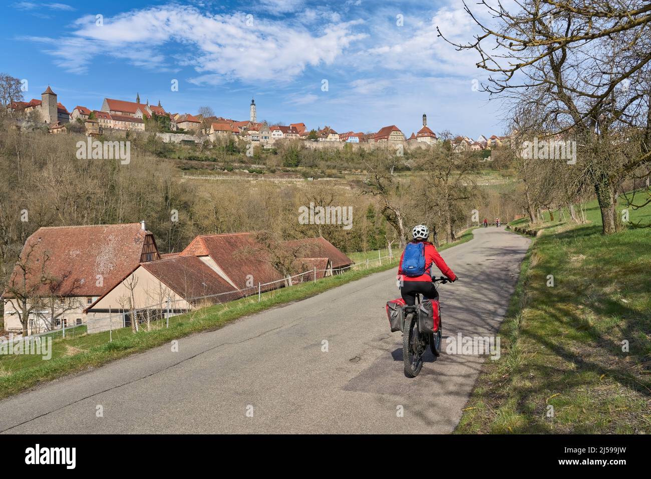 Belle femme de la ville lors d'une visite à vélo sur la célèbre route allemande des châteaux, au-dessous de la ligne d'horizon médiévale de Rothenburg ob der Tauber, Bavière, Allemagne Banque D'Images