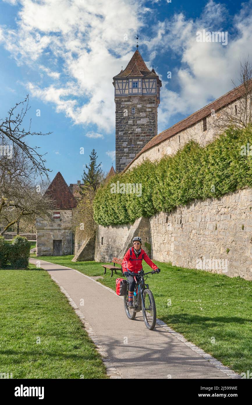 Belle femme de la ville lors d'une visite à vélo sur la célèbre route allemande des châteaux, au-dessous de la ligne d'horizon médiévale de Rothenburg ob der Tauber, Bavière, Allemagne Banque D'Images