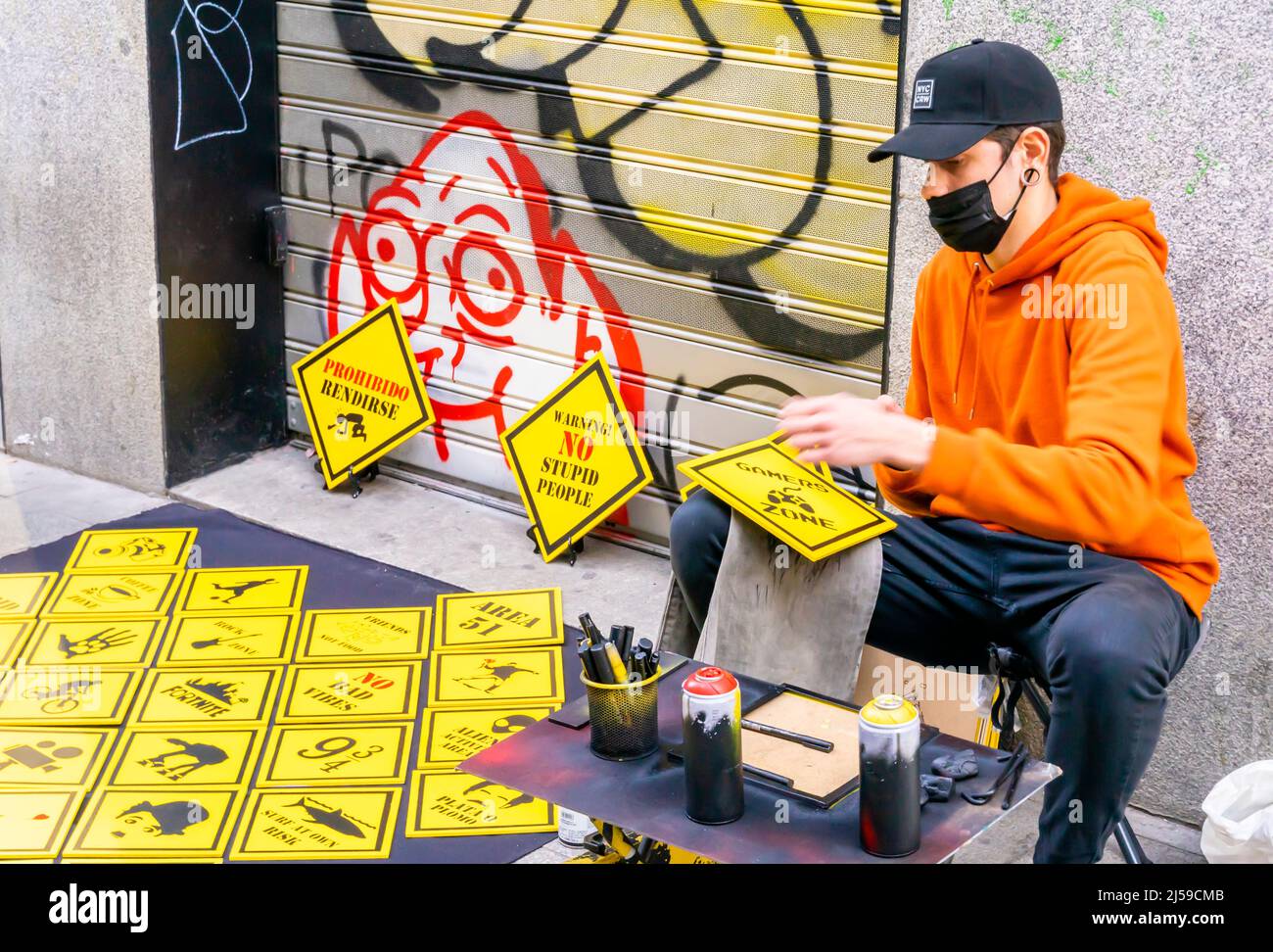 Artiste de rue dans le masque de visage peinture de panneaux de rue rombiques jaunes et les vendant sur le terrain à c Fuencarral, Malasana, Madrid, Espagne Banque D'Images