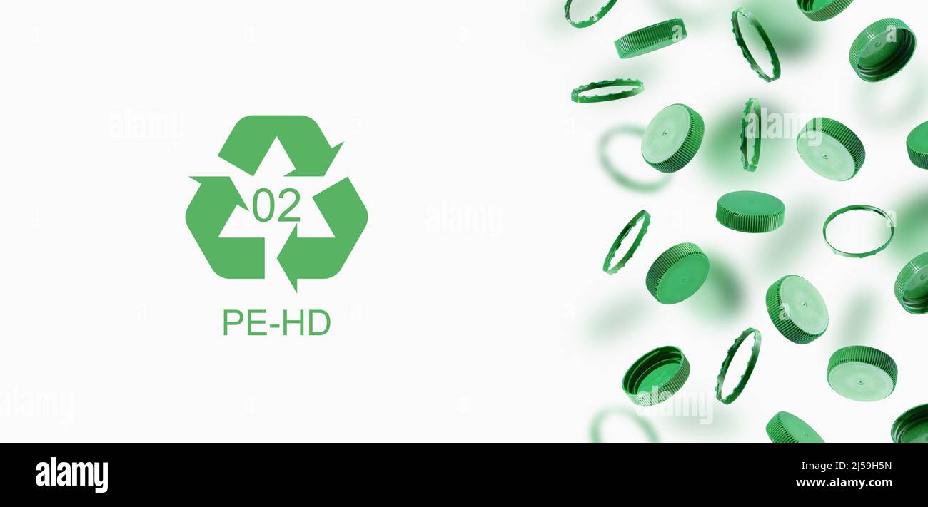 Bouchons de bouteille verts, symbole de recyclage sur fond gris. Les bouchons en plastique se vident dans l'air. Le concept de sécurité contre les dommages environnementaux. Banque D'Images