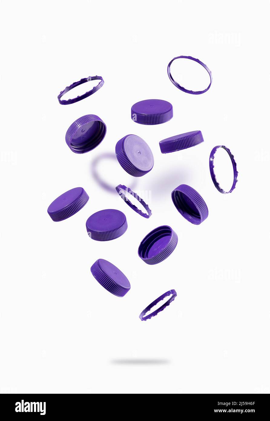 Bouchons de bouteilles en plastique pour le recyclage des vols sur fond blanc. Les capuchons en plastique volent et flottent dans l'air. L'idée de la durabilité environnementale. Banque D'Images