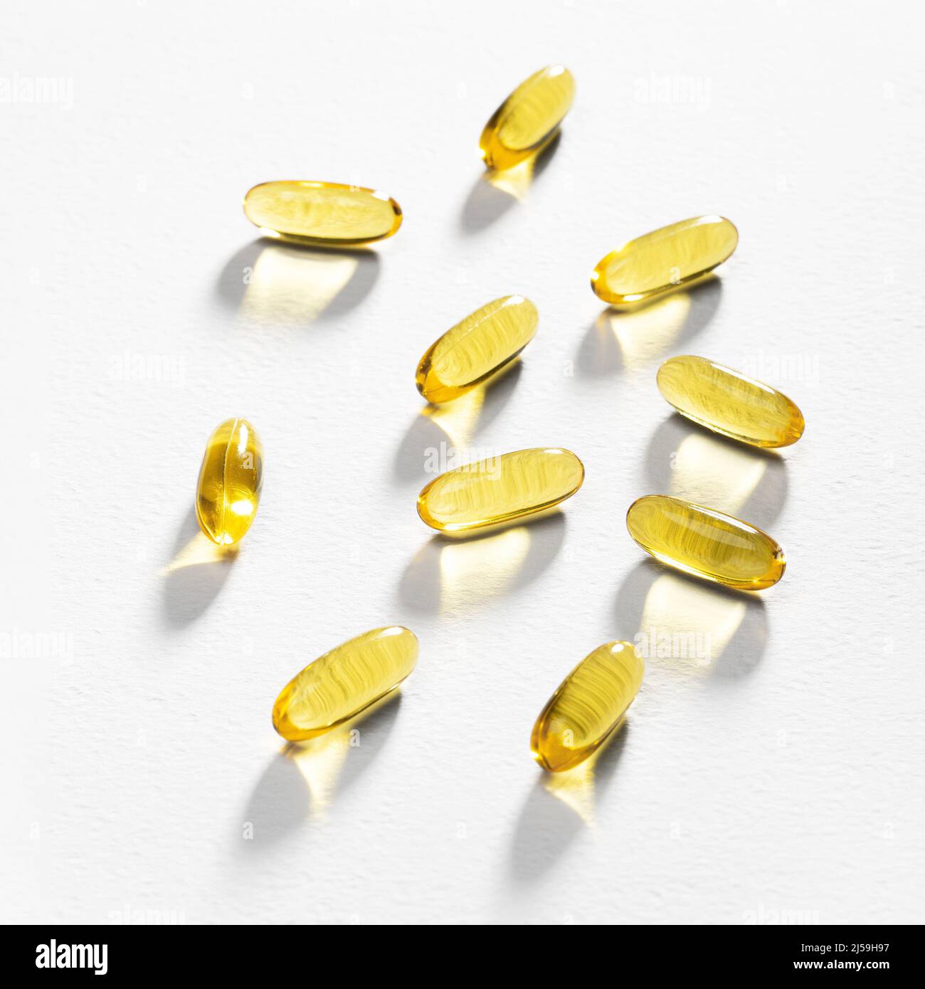 La lumière du soleil passe à travers quelques capsules Omega-3 sur un fond blanc. Caustiques lumière. Gels à base d'huile de poisson. Soutien médical et traitement. Banque D'Images