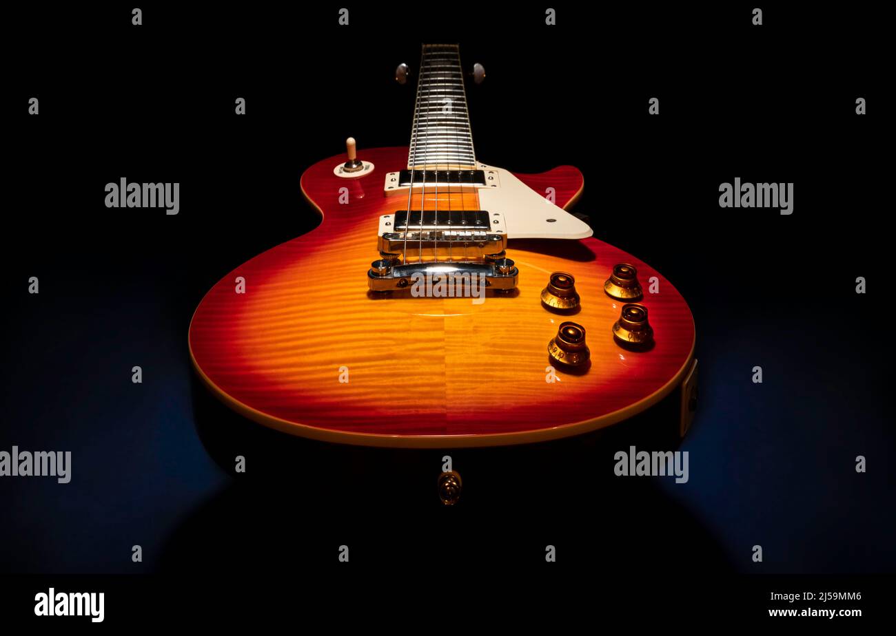 Belle photo de produit d'un rouge orange brun cerise Sunburst corps solide guitare électrique sur un fond sombre (noir). Banque D'Images