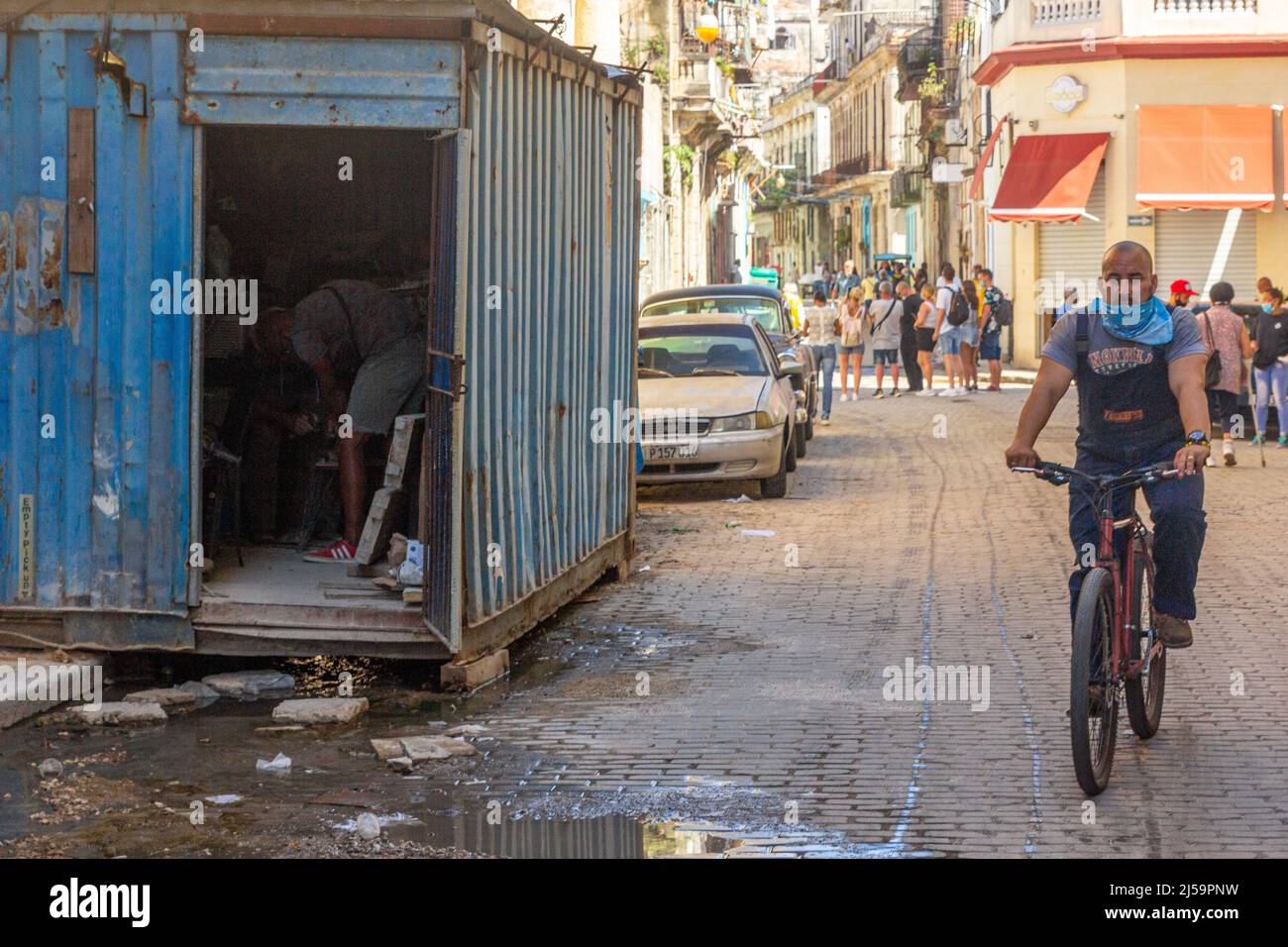 L'eau sale est vue par un conteneur de fret qui est utilisé comme stockage. D'autres Cubains sont vus dans leurs routines normales dans le pavé Banque D'Images