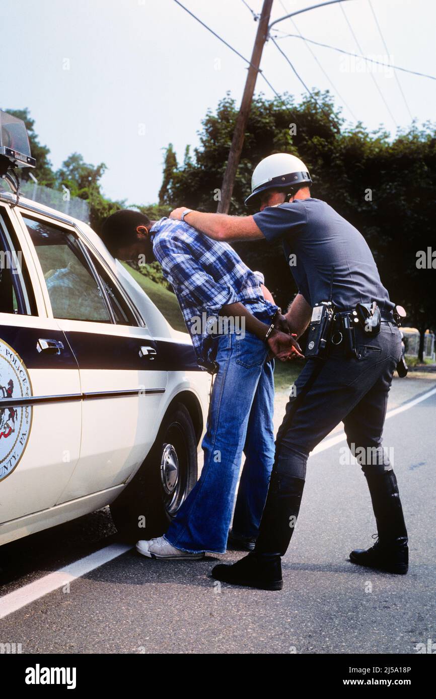 1970S HOMME CAUCASIEN POLICIER MENTANT L'HOMME AFRO-AMÉRICAIN À CÔTÉ DE LA VOITURE DE PATROUILLE - KP3048 HAR001 PERSONNES HARS INSPIRATION AUTOMOBILE HOMMES ORDRE DE RISQUE AGENT D'ARRESTATION CONFIANCE VOLEUR VOL DENIM TRANSPORT VOL VOLEUR COP VOL PROTÉGER PROTECTION AFRO-AMÉRICAINS COURAGE AFRO-AMÉRICAIN ET AUTOS NOIR FIERTÉ ETHNIQUE LES PROFESSIONS DE L'AUTORITÉ UNIFORMES CAMBRIOLAGE CONNEXION PATROUILLE CONCEPTUELLE AUTOMOBILES À CÔTÉ DE VÉHICULES FELONY SUSPECTS OFFICIERS POLICIERS BLEU JEANS COPS ILLÉGAL INFORMEL MOYEN-ADULTE HOMME MOYEN-ADULTE EN BORDURE DE ROUTE TWERA JEUNE ADULTE INSIGNE D'HOMME INSIGNES DÉCONTRACTÉ RACE BLANCHE HAR001 Banque D'Images