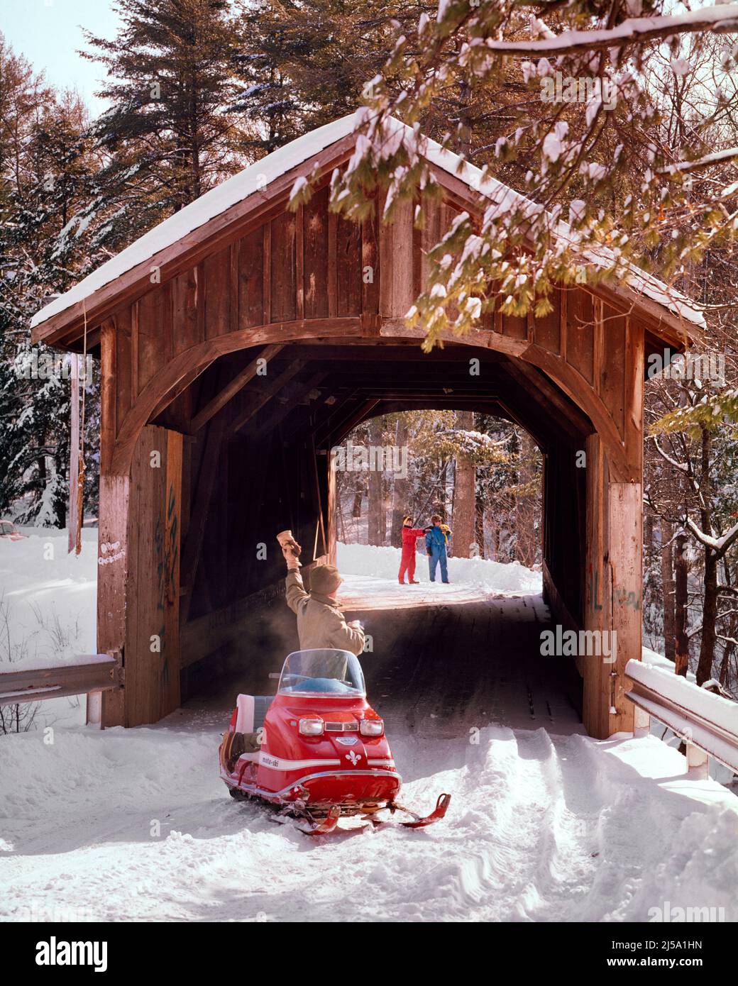 1970S HOMME SUR UNE ROUTE ENNEIGÉE AVEC MOTO-SKI MOTONEIGE EN CHEMIN VERS UN COUPLE DE RANDONNÉE DE L'AUTRE CÔTÉ DE BOIS RUSTIQUE COUVERT PONT - KW3414 HAR001 SALUTATION HARS EMBALLÉ PAR VÉHICULE DE BIENVENUE JEUNE ADULTE STYLE DE VIE FEMMES RURAL MAISON VIE COPIE ESPACE AMITIÉ FEMMES PERSONNES HOMMES APPELANT TRANSPORT RANDONNÉE MOTONEIGE D'ÂGE MOYEN HOMME D'ÂGE MOYEN HIVER COUVERT RUSTIQUE AVENTURE DÉCOUVERTE EXCITATION LOISIRS D'ON TO SIGNAUX HIVER JEUNE HOMME ADULTE JEUNE FEMME ADULTE RACE BLANCHE HAR001 ANCIENNE Banque D'Images