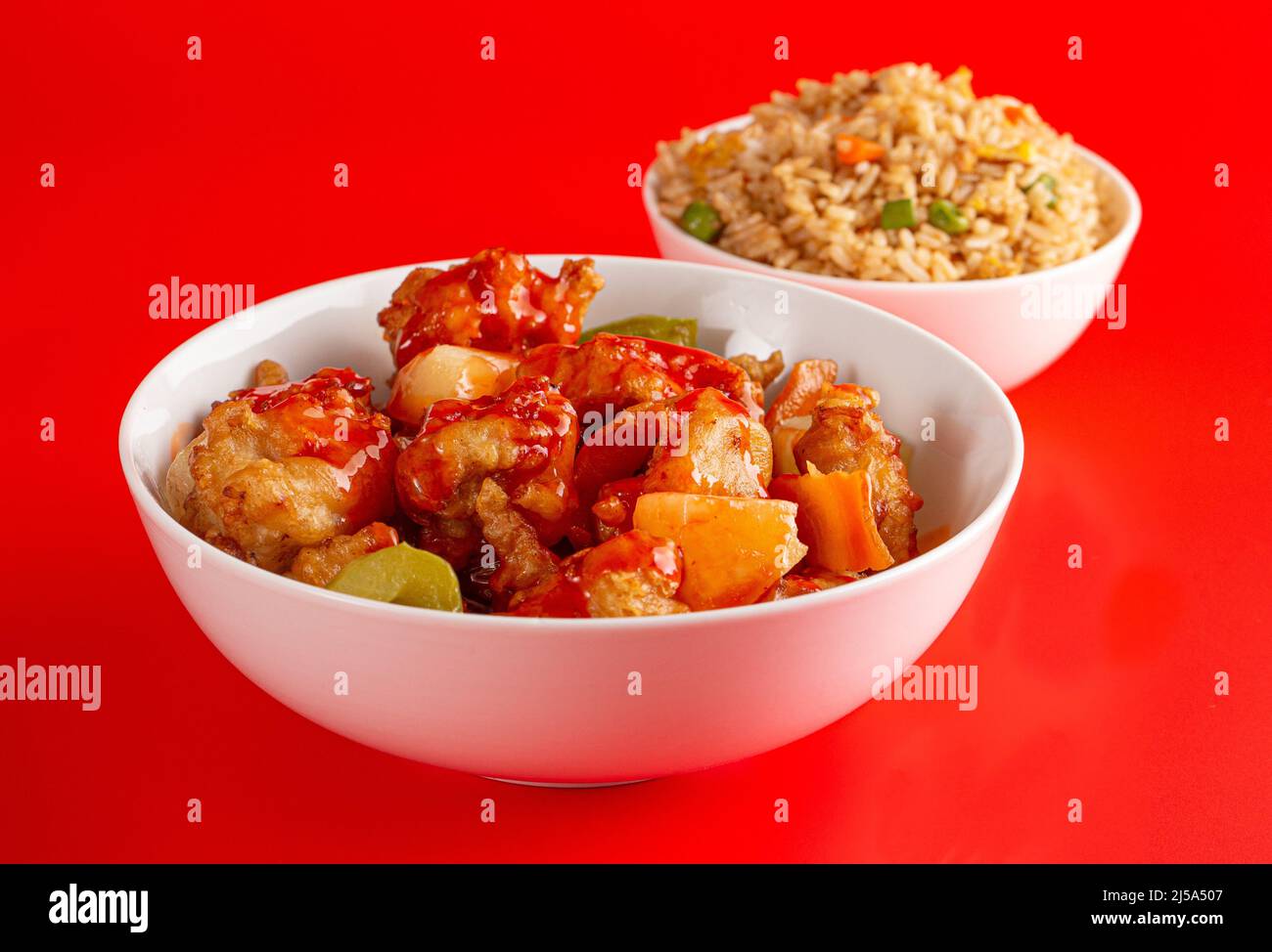 Un bol de poulet et de légumes frits avec une sauce sucrée et couchée et du riz frit Banque D'Images