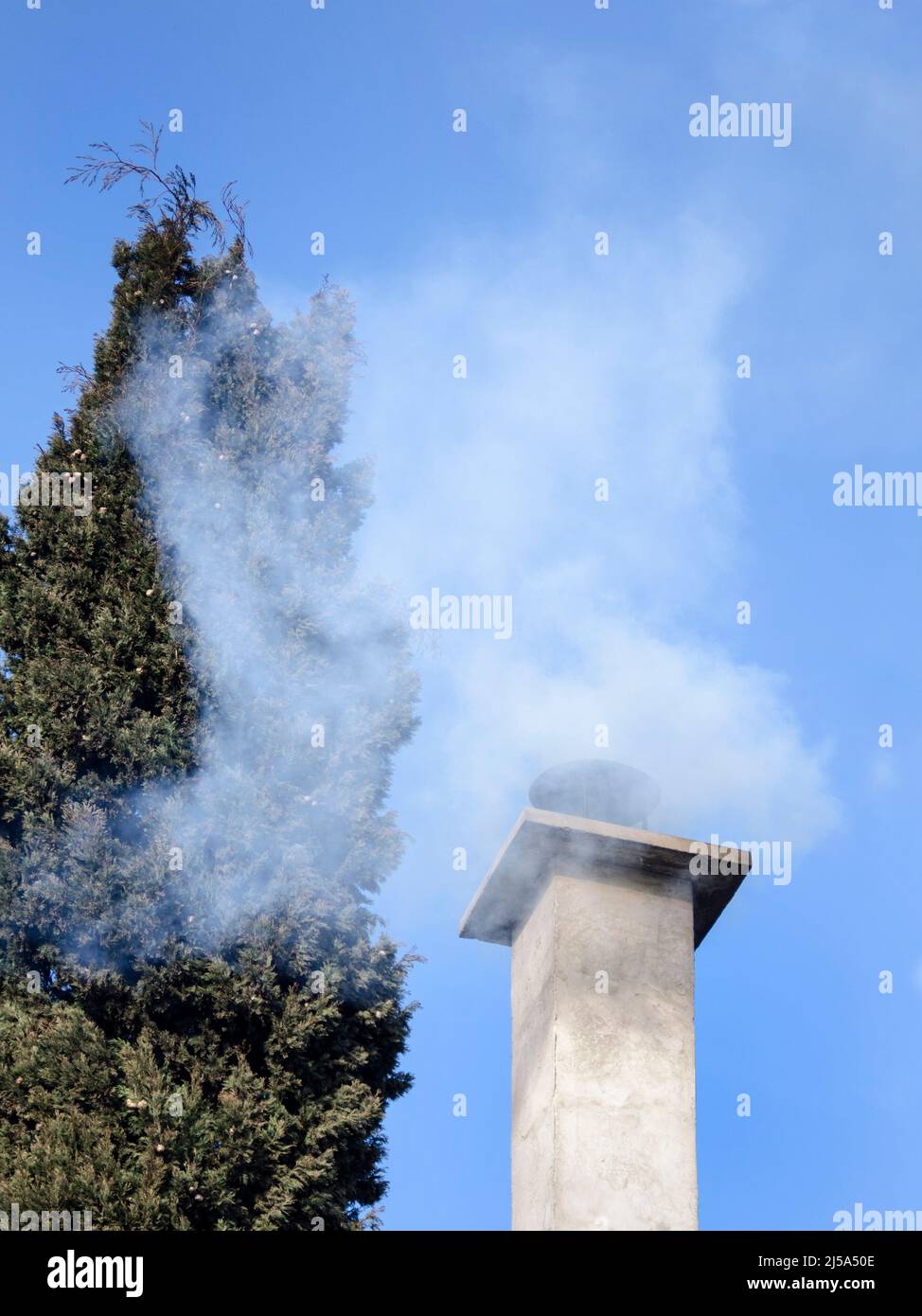 Cheminée Smokey en milieu d'hiver sur ciel bleu Banque D'Images