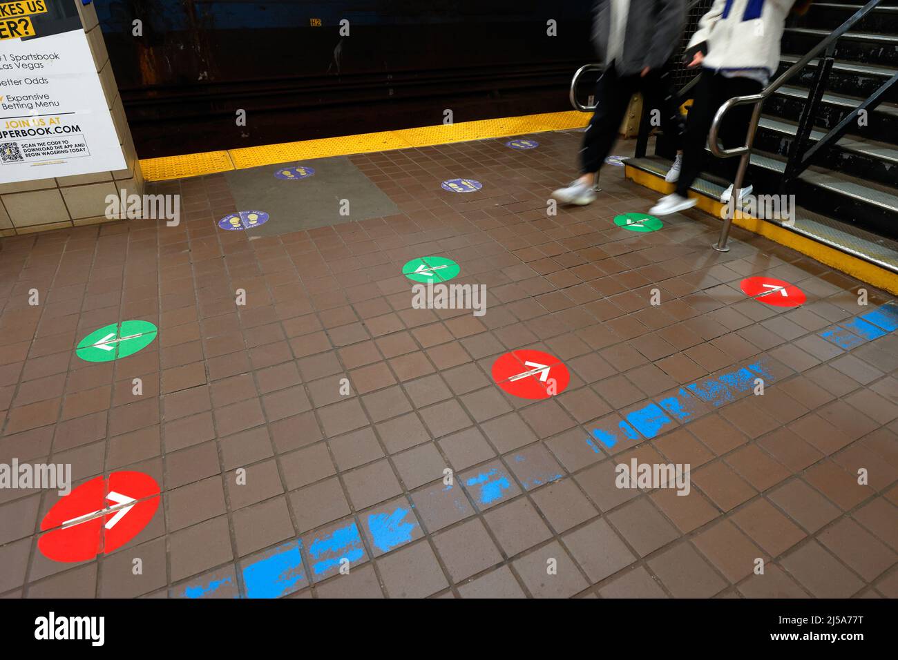 Des flèches directionnelles et des décalcomanies sociales sur le sol d'un système de transport souterrain. Banque D'Images