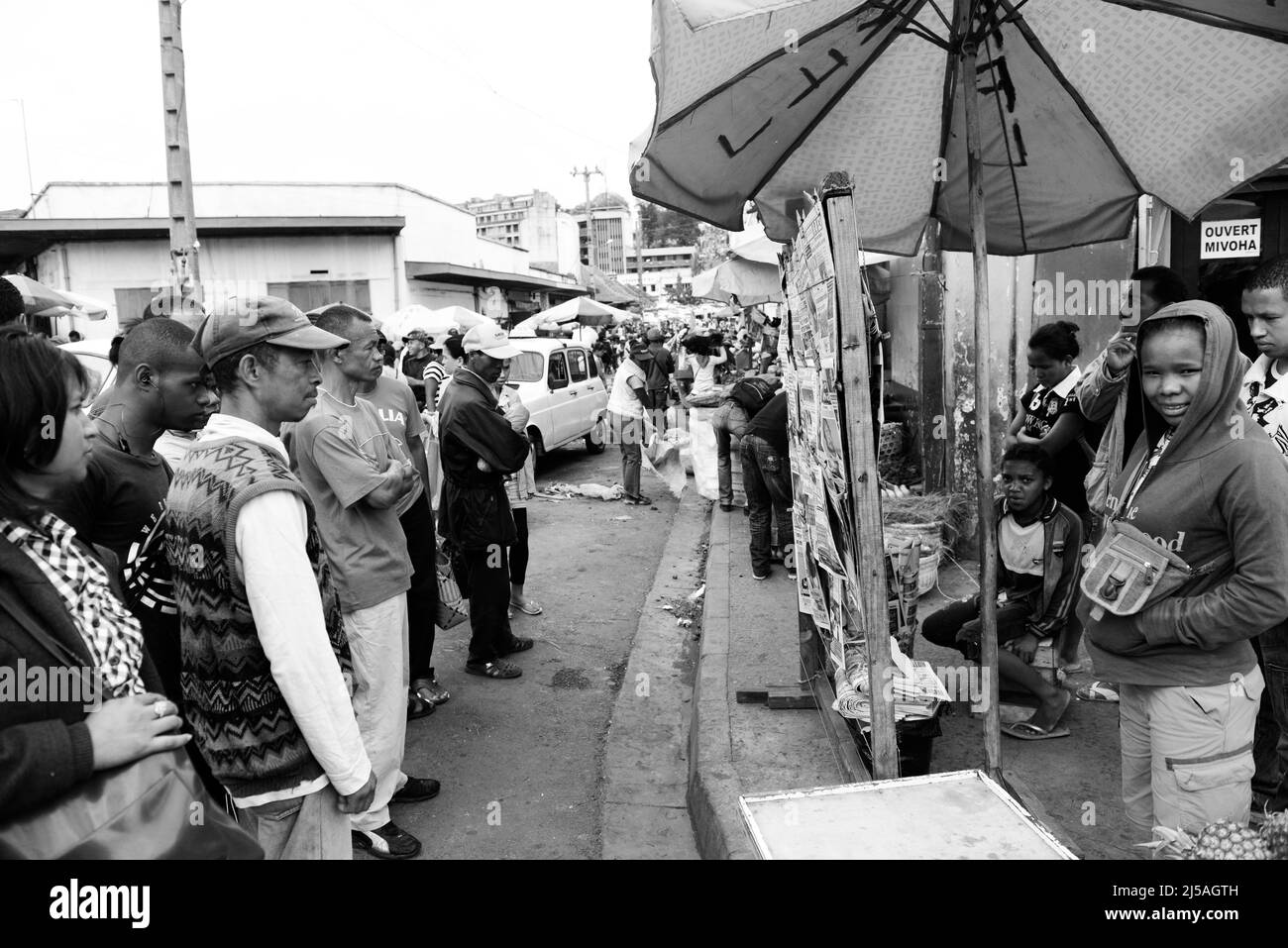 Des hommes et des femmes malgaches lisant les journaux du matin dans un kiosque à journaux avant les élections générales de décembre 2013. Antananarivo, Madagascar. Banque D'Images