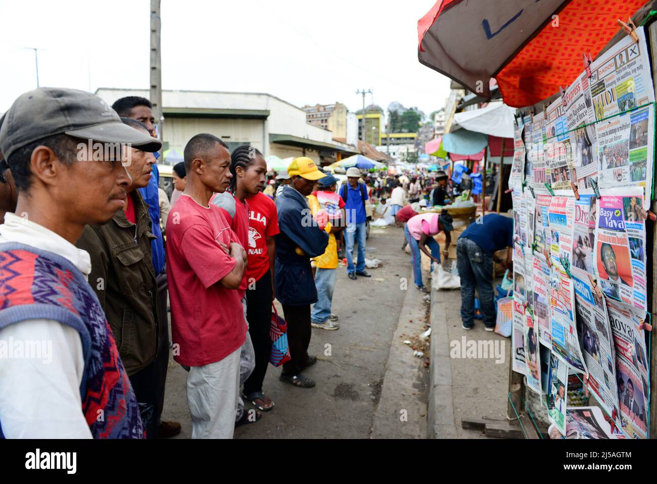 Des hommes et des femmes malgaches lisant les journaux du matin dans un kiosque à journaux avant les élections générales de décembre 2013. Antananarivo, Madagascar. Banque D'Images