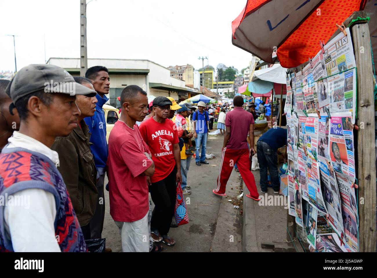 Des hommes et des femmes malgaches lisant les journaux du matin dans un kiosque à journaux avant les élections générales de décembre 2013. Antananarivo, Madagascar. Banque D'Images