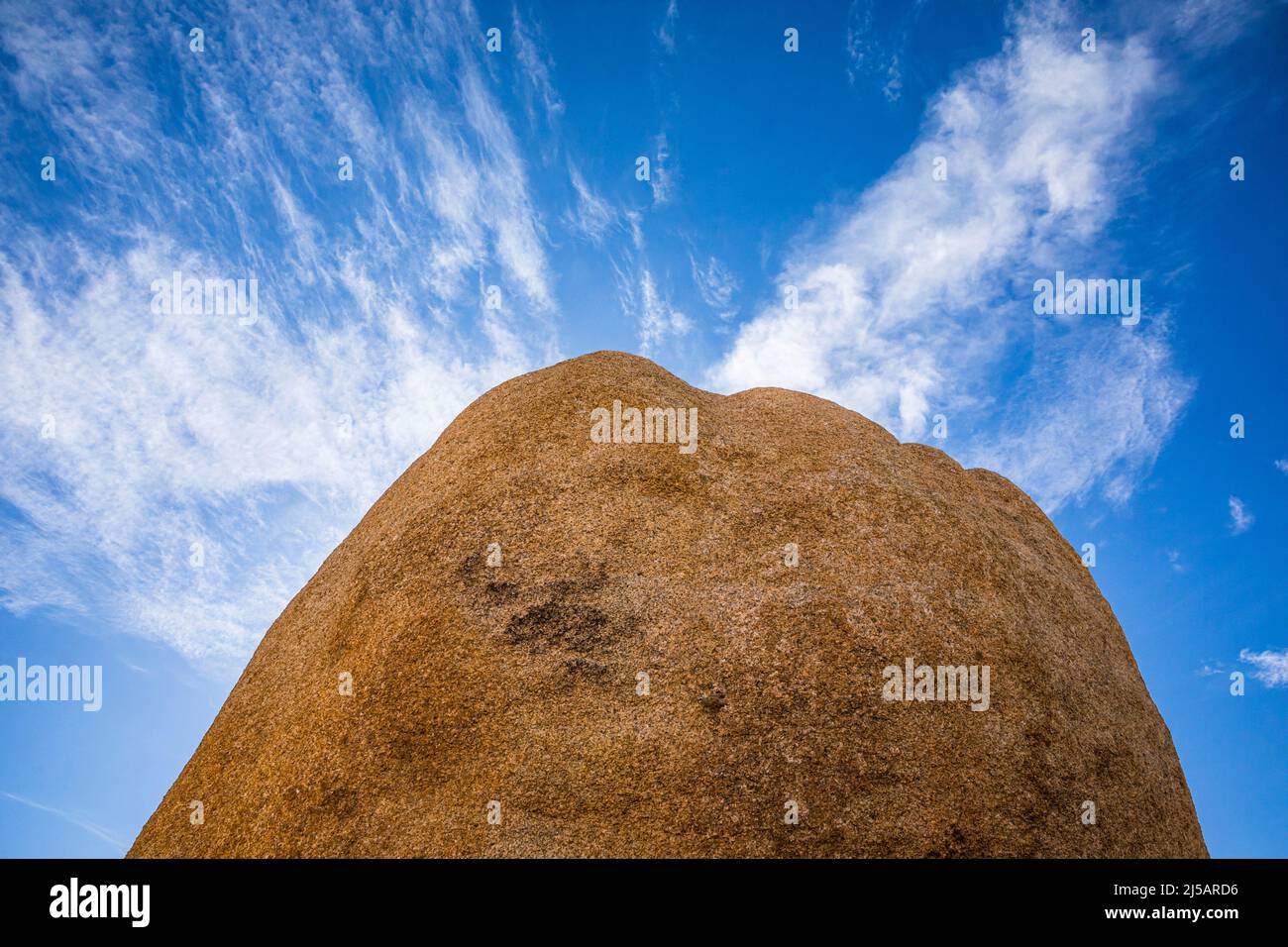 Un gros rocher contre le ciel bleu et les nuages plus sombres. Banque D'Images