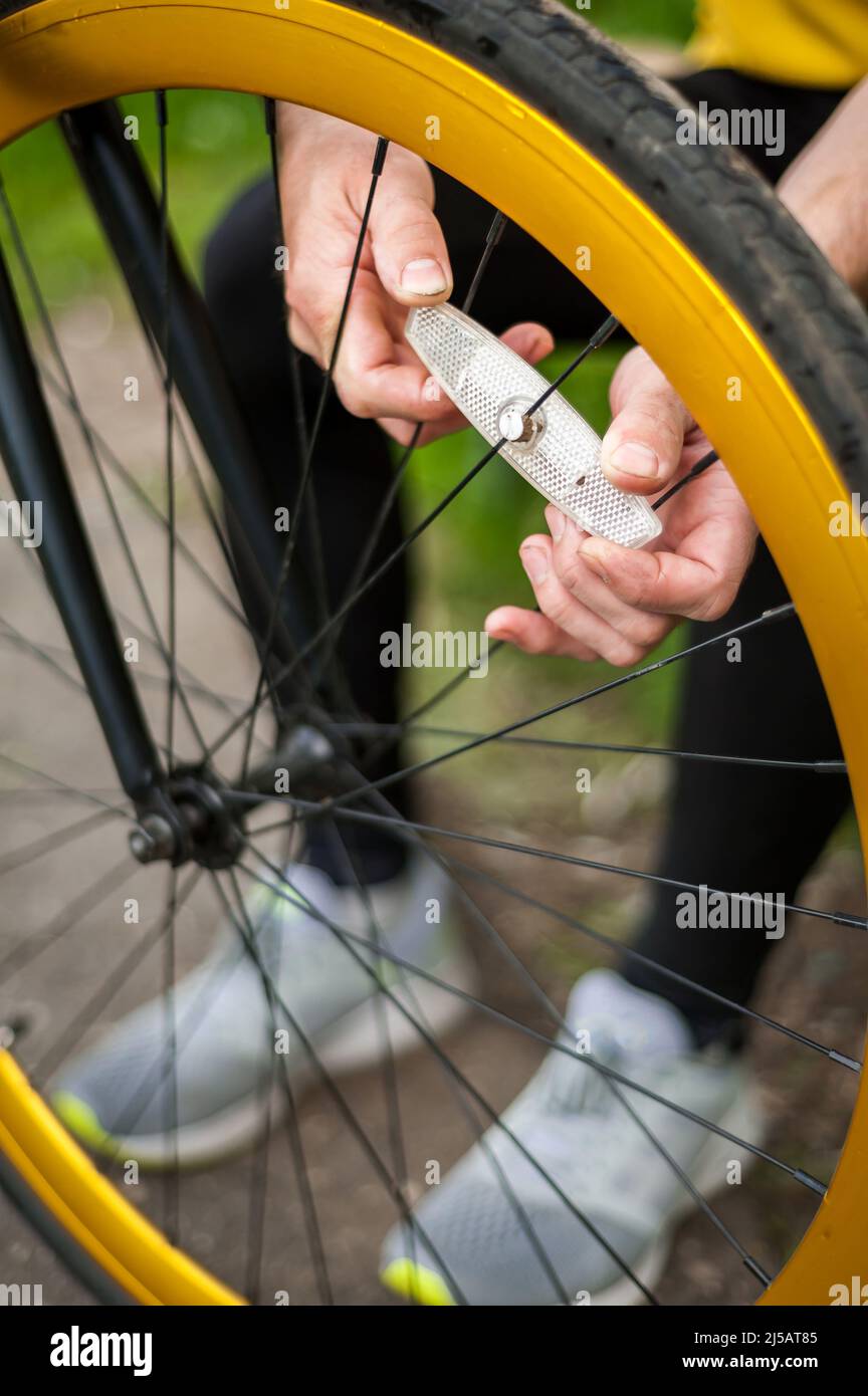 Un jeune homme répare la roue de son vélo. Il le fait en plein air. Gros plan. Banque D'Images