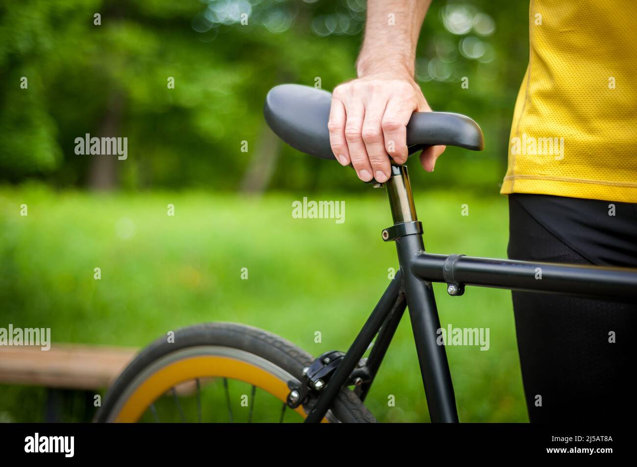 Cycliste avec son vélo, gros plan. Photographie en extérieur. Vous pouvez voir ses mains et la roue. Banque D'Images