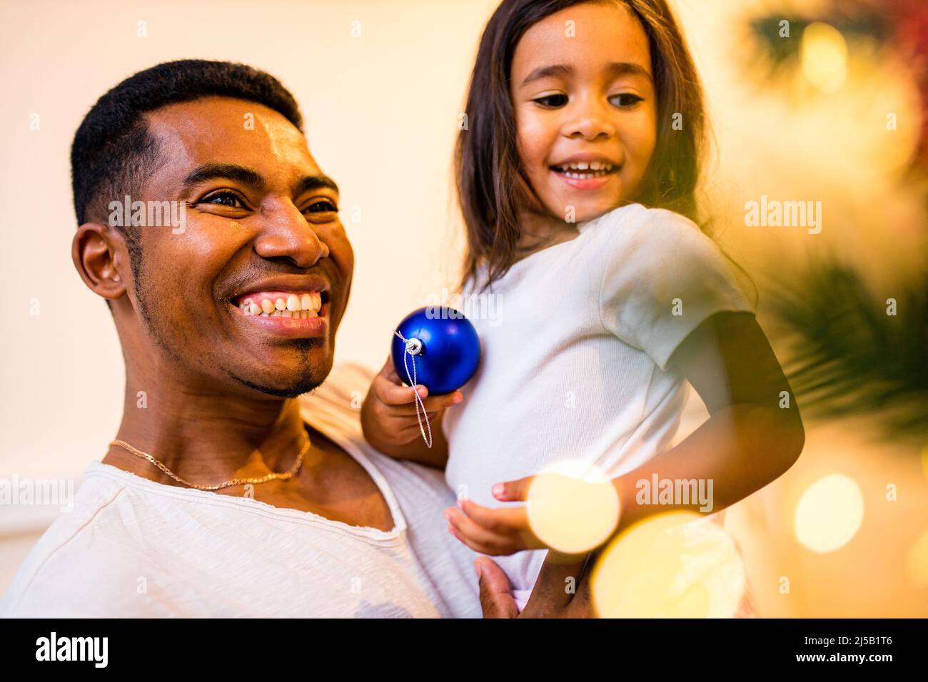 joyeux père de race mixte et belle fille joyeuse décorant l'intérieur dans la salle de séjour Banque D'Images