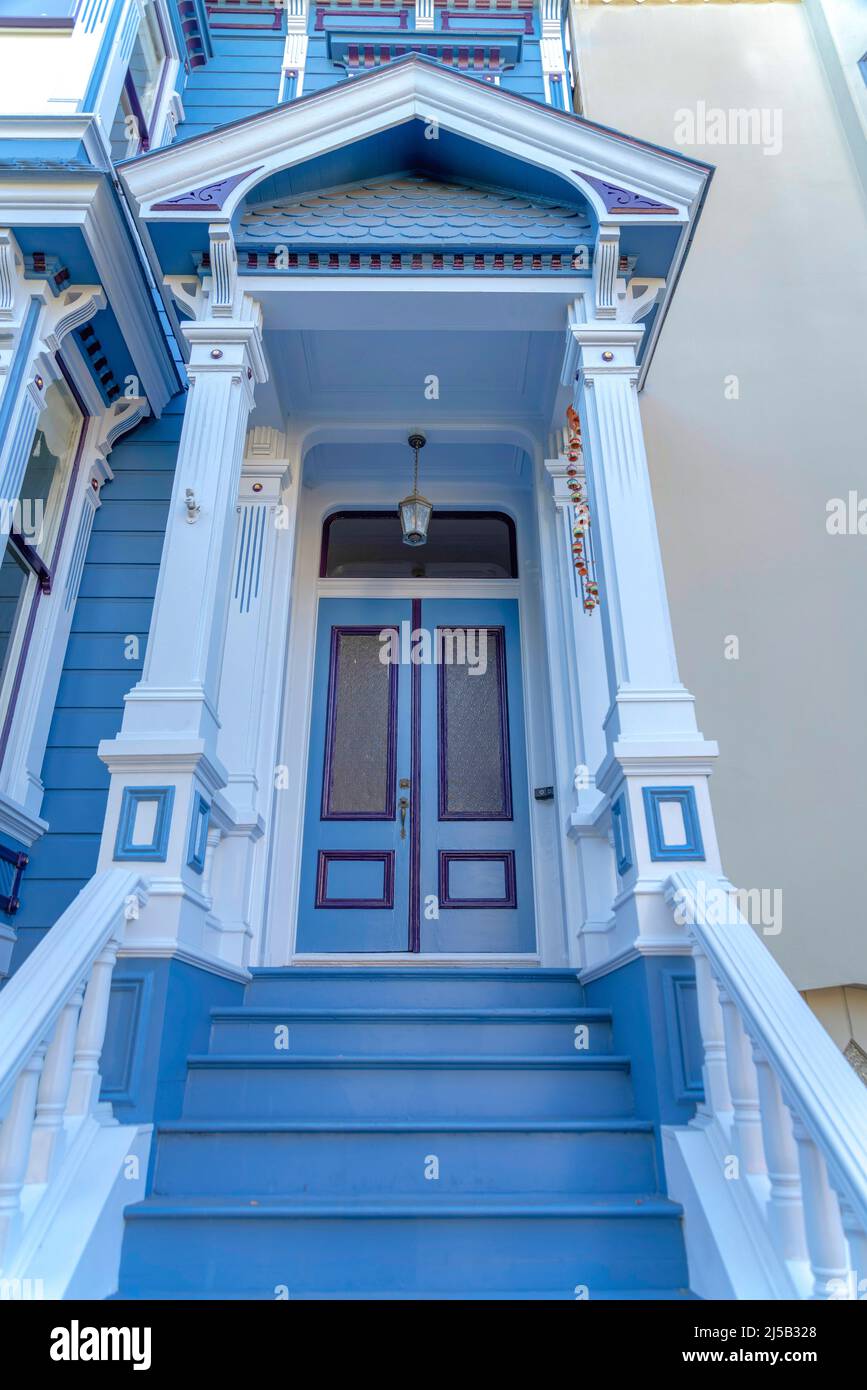 Extérieur de l'entrée de la maison de ville avec des garnitures de style victorien à San Francisco, Californie. Il y a un escalier avec des marches bleues menant à la porte double avec Banque D'Images