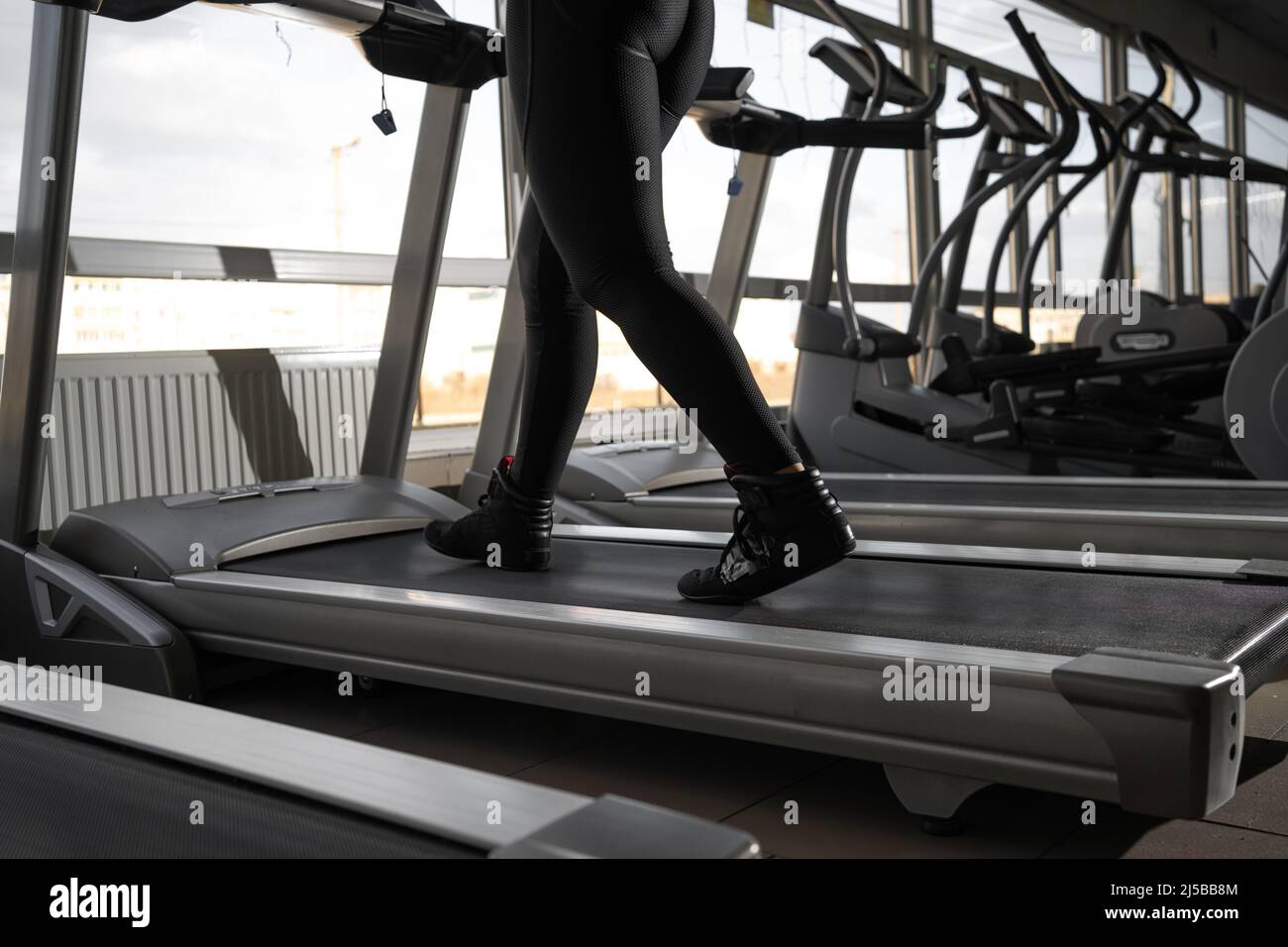 Entraînement cardio. Vue latérale des jambes baskets de course fitness fille de course sur la piste de tapis roulant, femme avec des jambes musculaires dans la salle de gym. Pas de face, espace de copie Banque D'Images