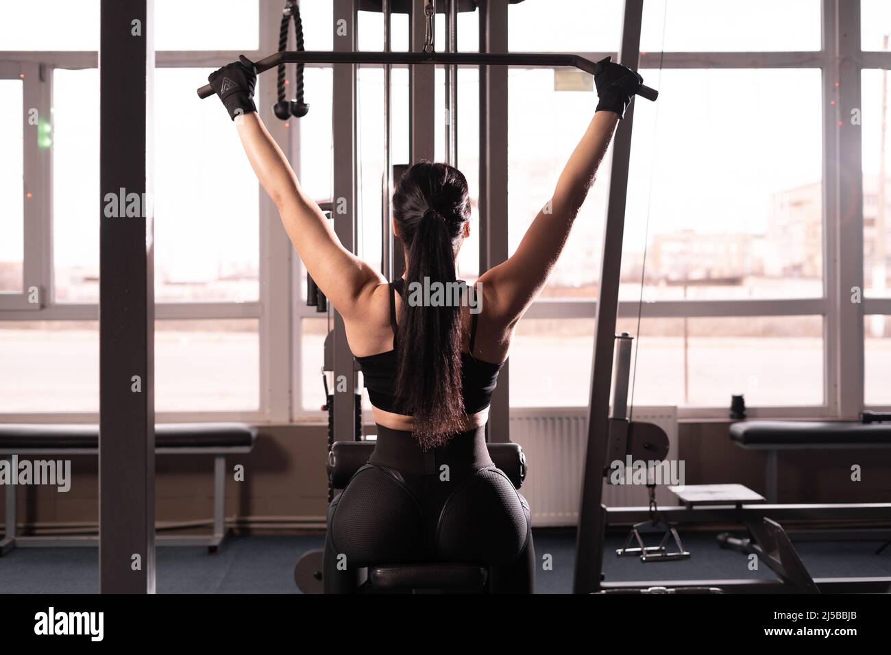 Machine à abaisser l'épaule. Une femme de fitness s'entraîne dans la salle  de gym. Exercice de force du haut du corps pour le haut du dos. Vue du dos  sans visage Photo