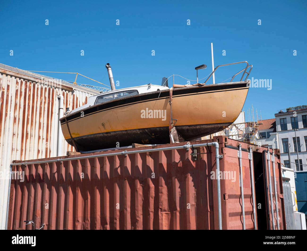 Le petit vieux bateau de plaisance est exposé sur un conteneur d'expédition Banque D'Images