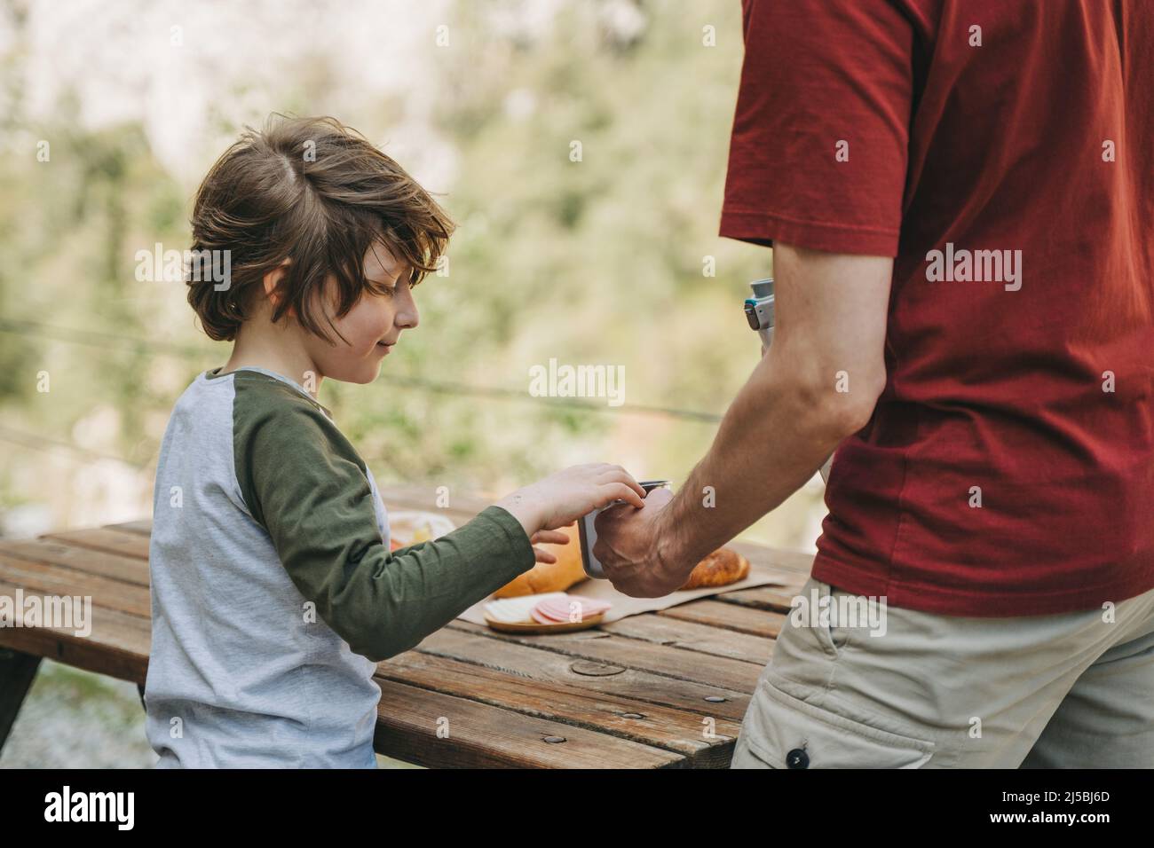 Vue rapprochée de son père et de son fils garçon d'école lors d'un pique-nique en famille dans les montagnes. Enfant et son père se reposent et pique-nique Banque D'Images